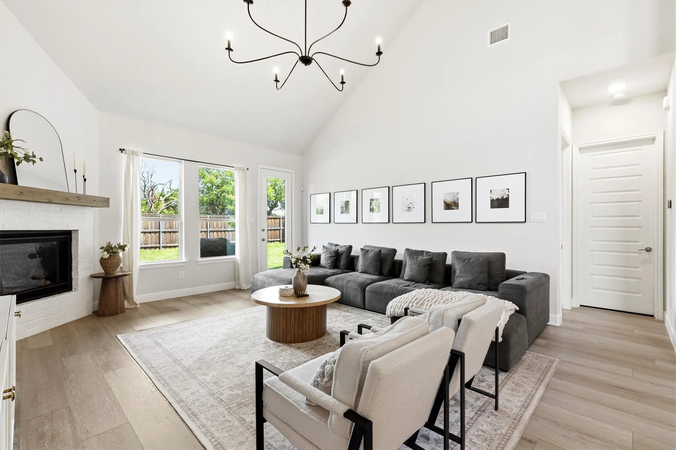 Vaulted living space featuring a corner fireplace with white brick surround and wood mantel