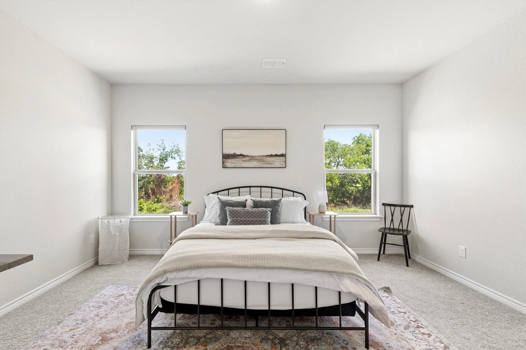 Carpeted bedroom featuring two windows, white baseboards, and light neutral wall paint