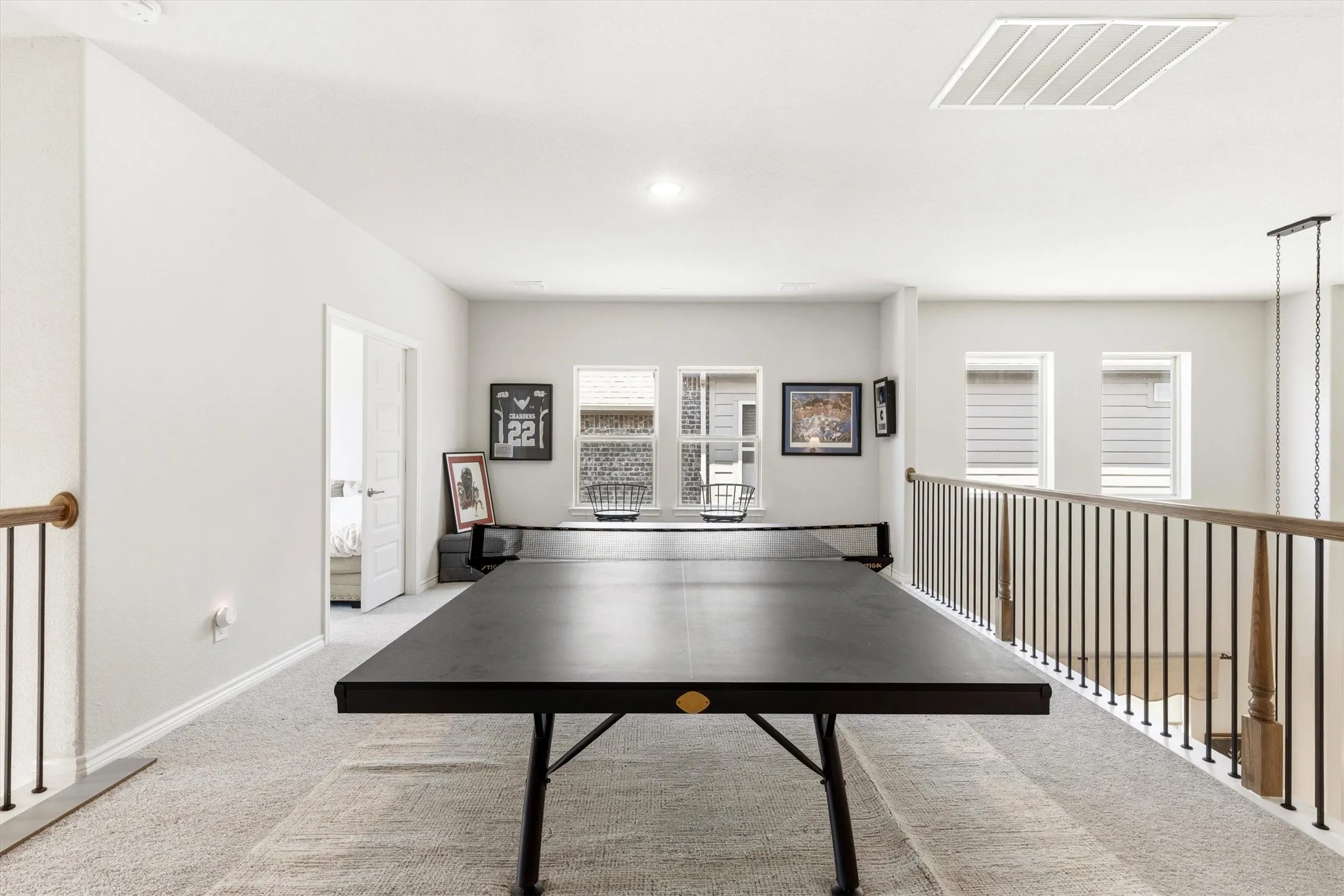 Spacious loft area featuring light-colored carpet flooring, white walls, and multiple windows with horizontal blinds