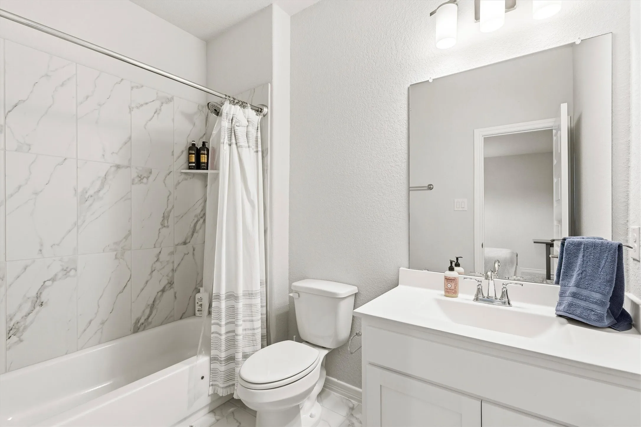 Bathroom featuring a white vanity with an integrated sink, polished chrome faucet, and a large unframed mirror