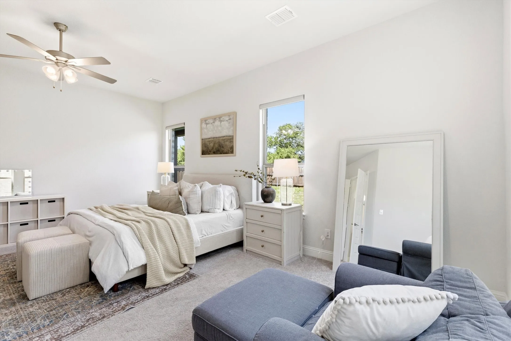 Spacious room with light-colored carpeting, a window providing natural light, and a ceiling fan with integrated lighting