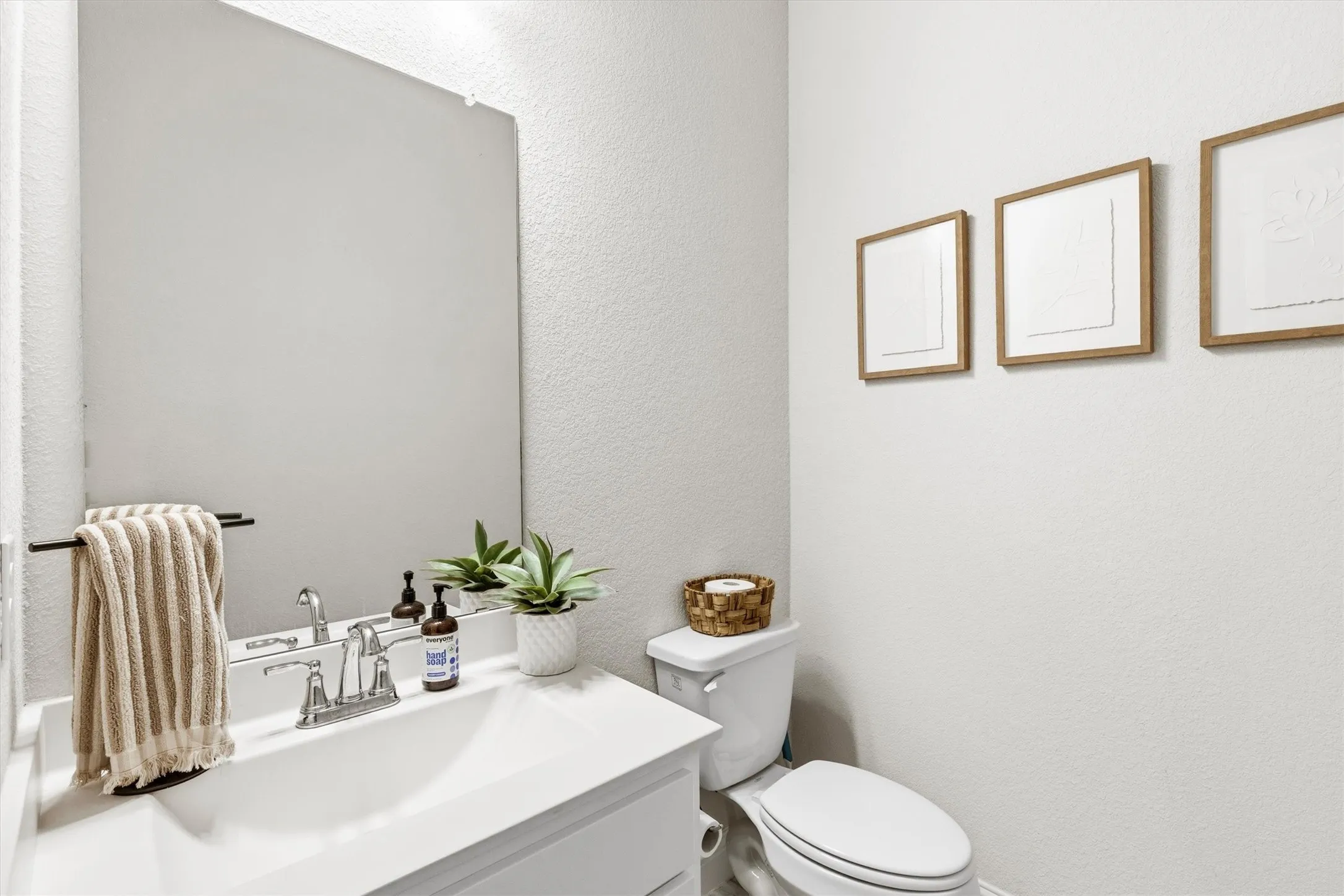 White vanity with an integrated rectangular sink, chrome faucet, and a large wall-mounted mirror