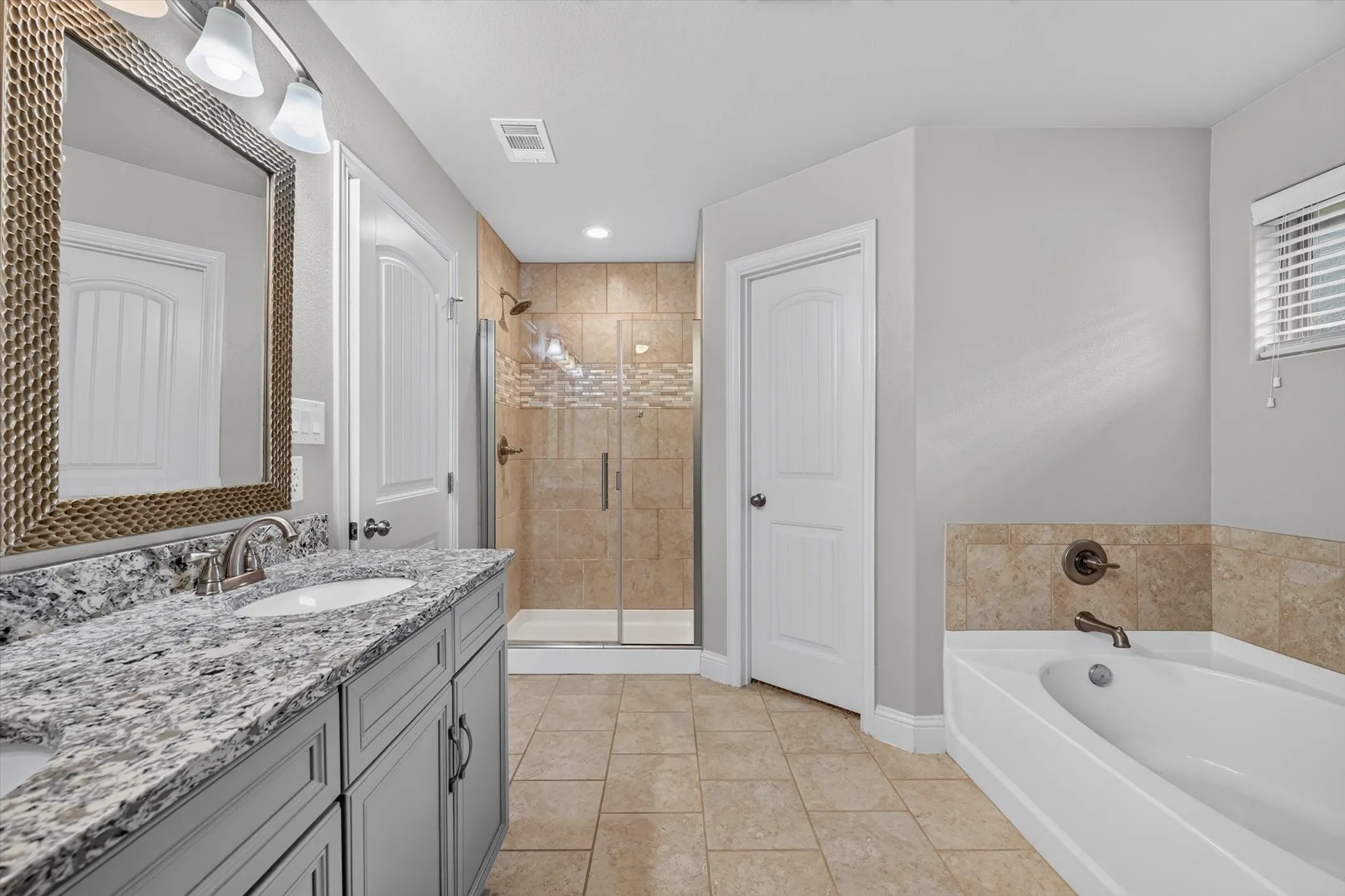 Dual-sink vanity with a speckled countertop, framed mirror, and chrome fixtures