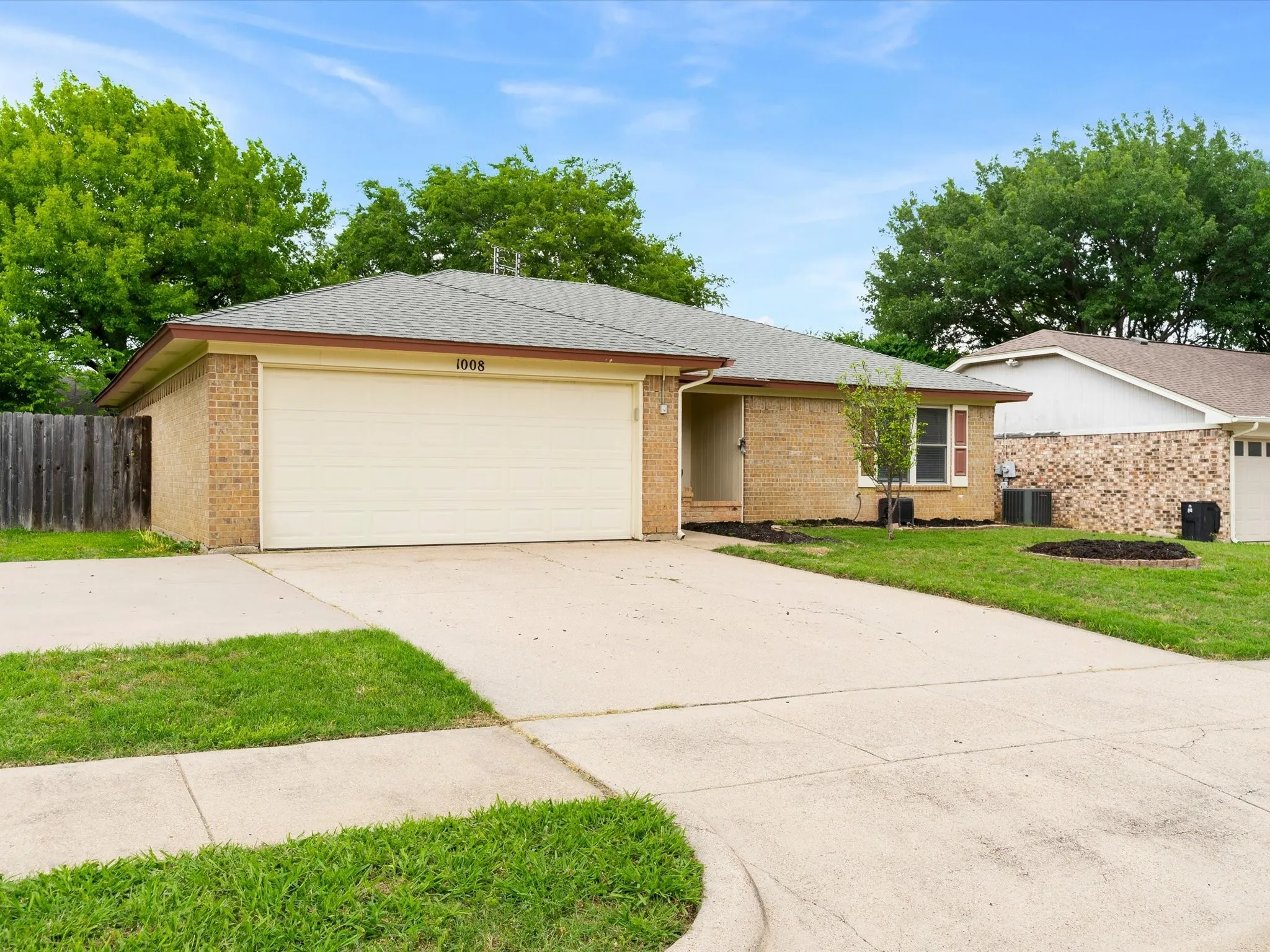 Front exterior of 1008 Green Ridge Terrace in Saginaw featuring mature landscaping, brick façade, and two-car garage.