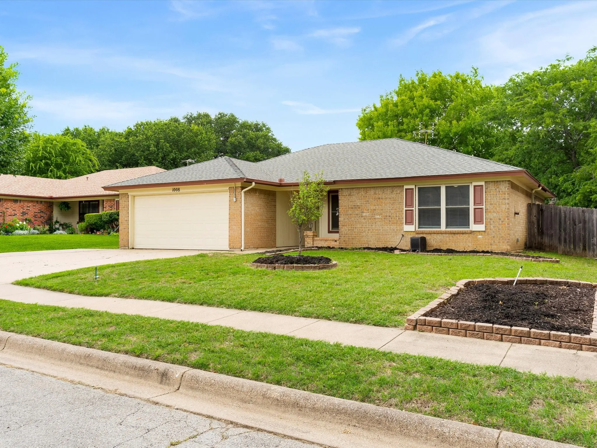 Front exterior of 1008 Green Ridge Terrace in Saginaw featuring mature landscaping, brick façade, and two-car garage.