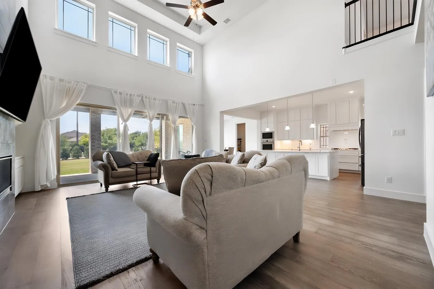 Open concept family room with high ceilings and glass sliding doors overlooking the beautiful backyard
