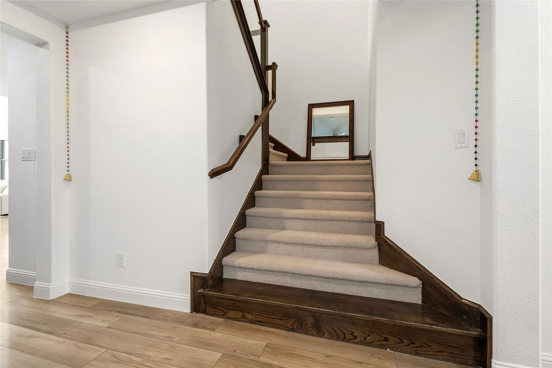 Staircase featuring wood-finish treads and risers, carpeted steps, and a dark wood-finish handrail