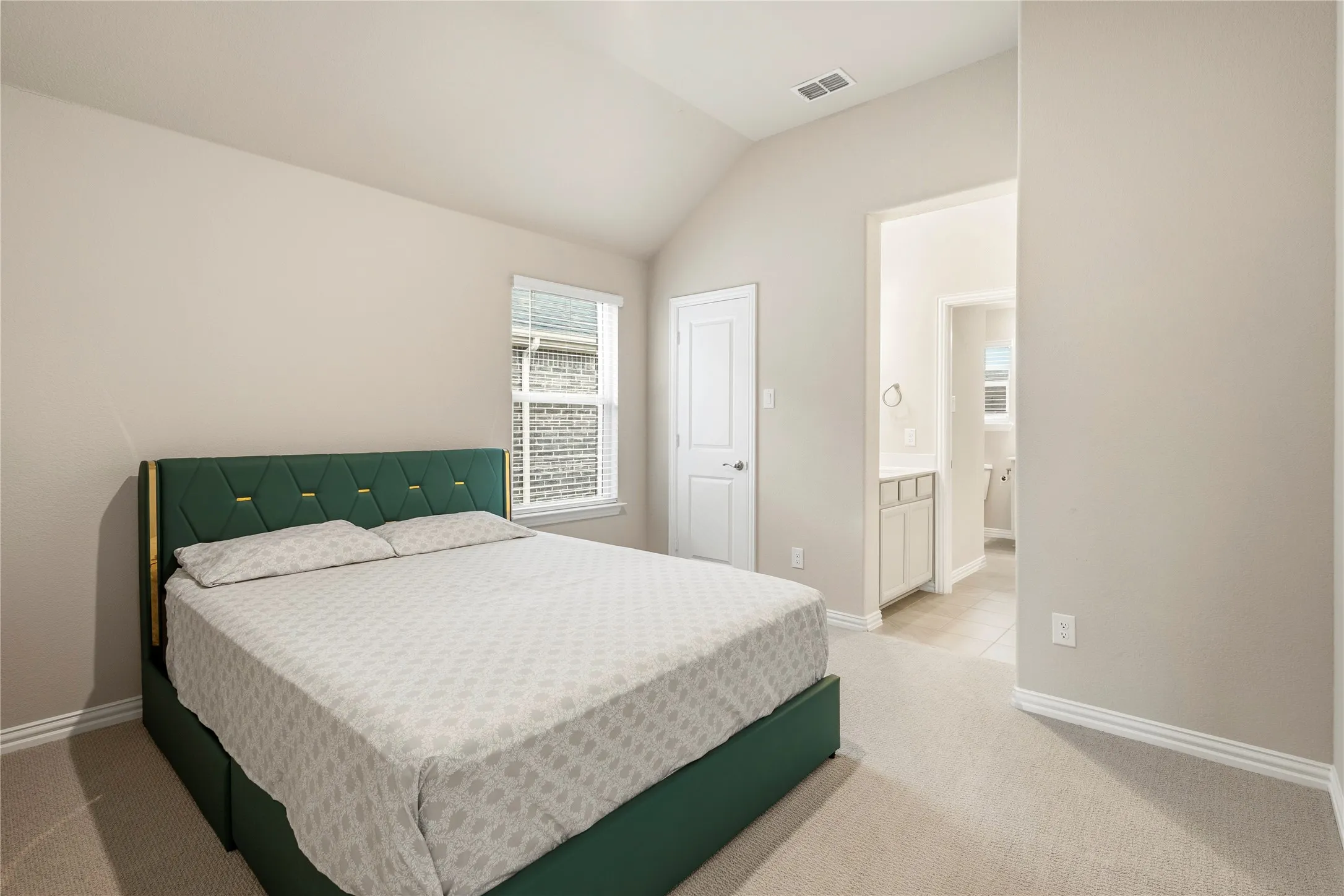 Bedroom featuring neutral-toned walls, vaulted ceiling, and carpet flooring