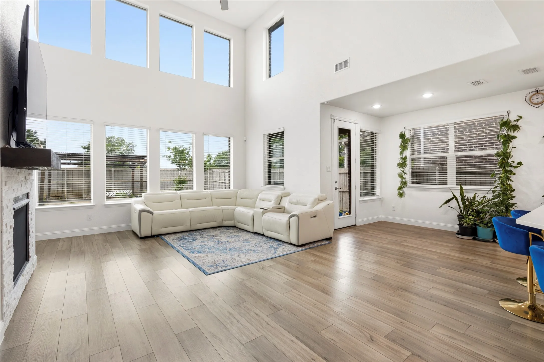 Spacious living area featuring high ceilings, a wall of large windows, and light wood-finish flooring