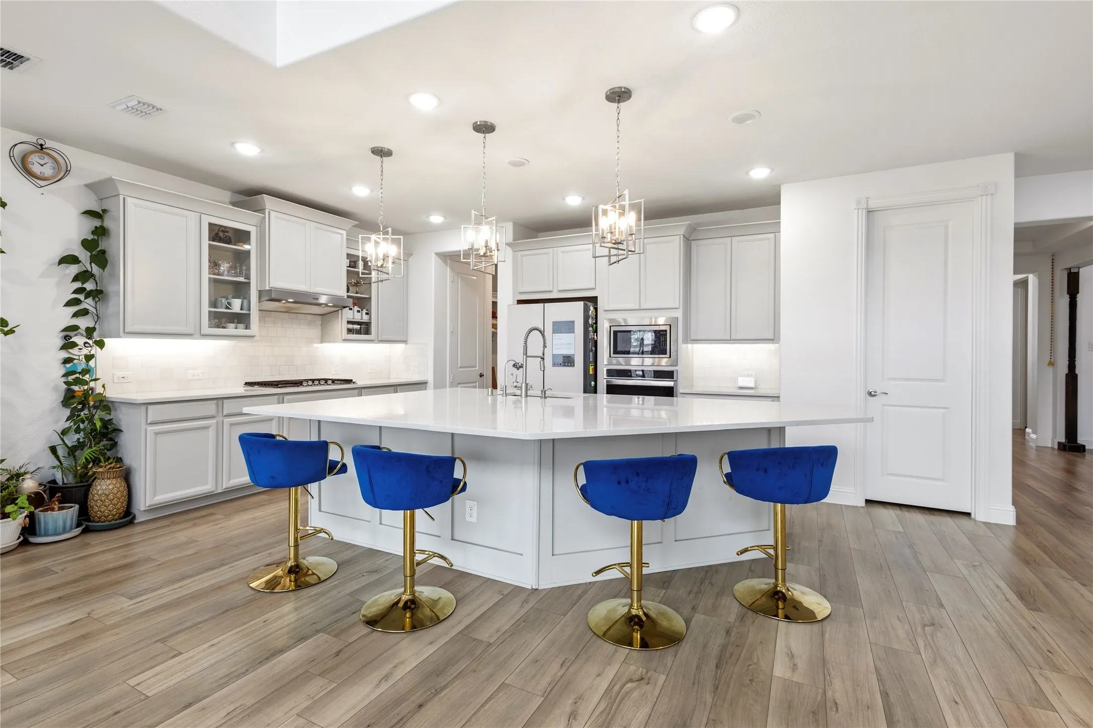 Spacious kitchen featuring a large central island, light-toned cabinetry, stainless steel appliances, wood-finish flooring, and recessed lighting