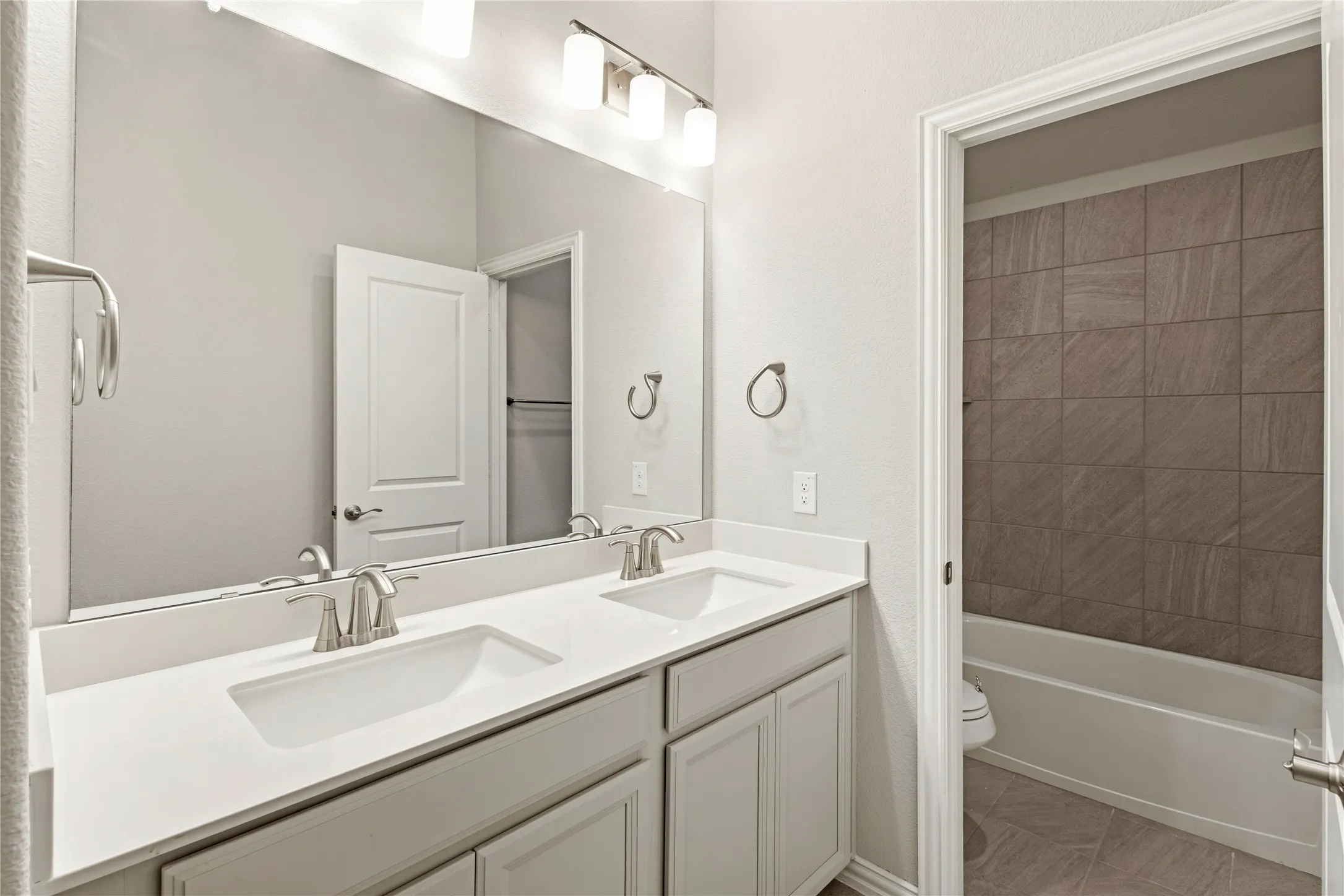 Bathroom featuring a dual vanity with white countertops, undermount sinks, and brushed nickel faucets