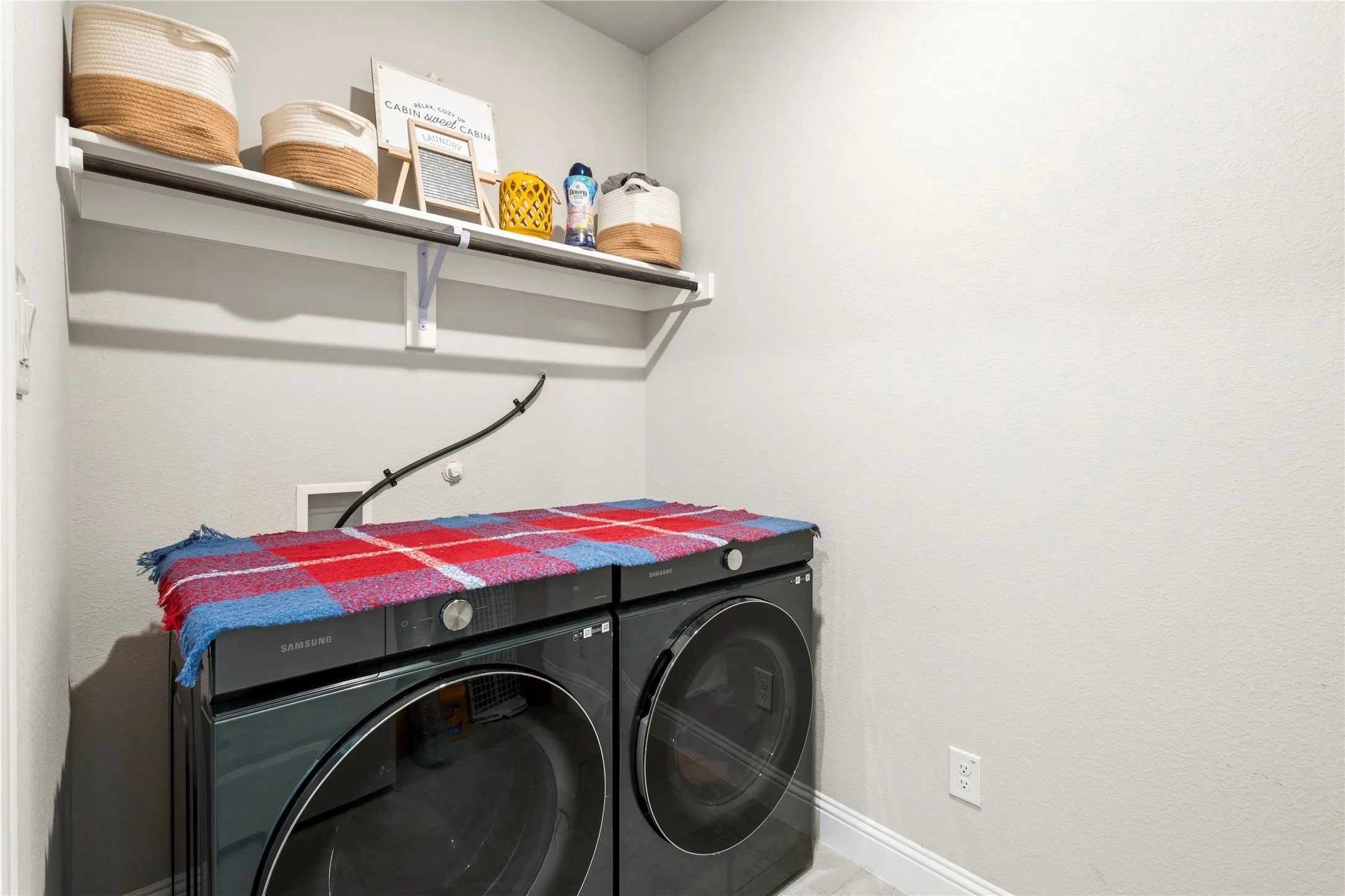 Dedicated laundry area featuring a wall-mounted shelf and clothes hanging rod
