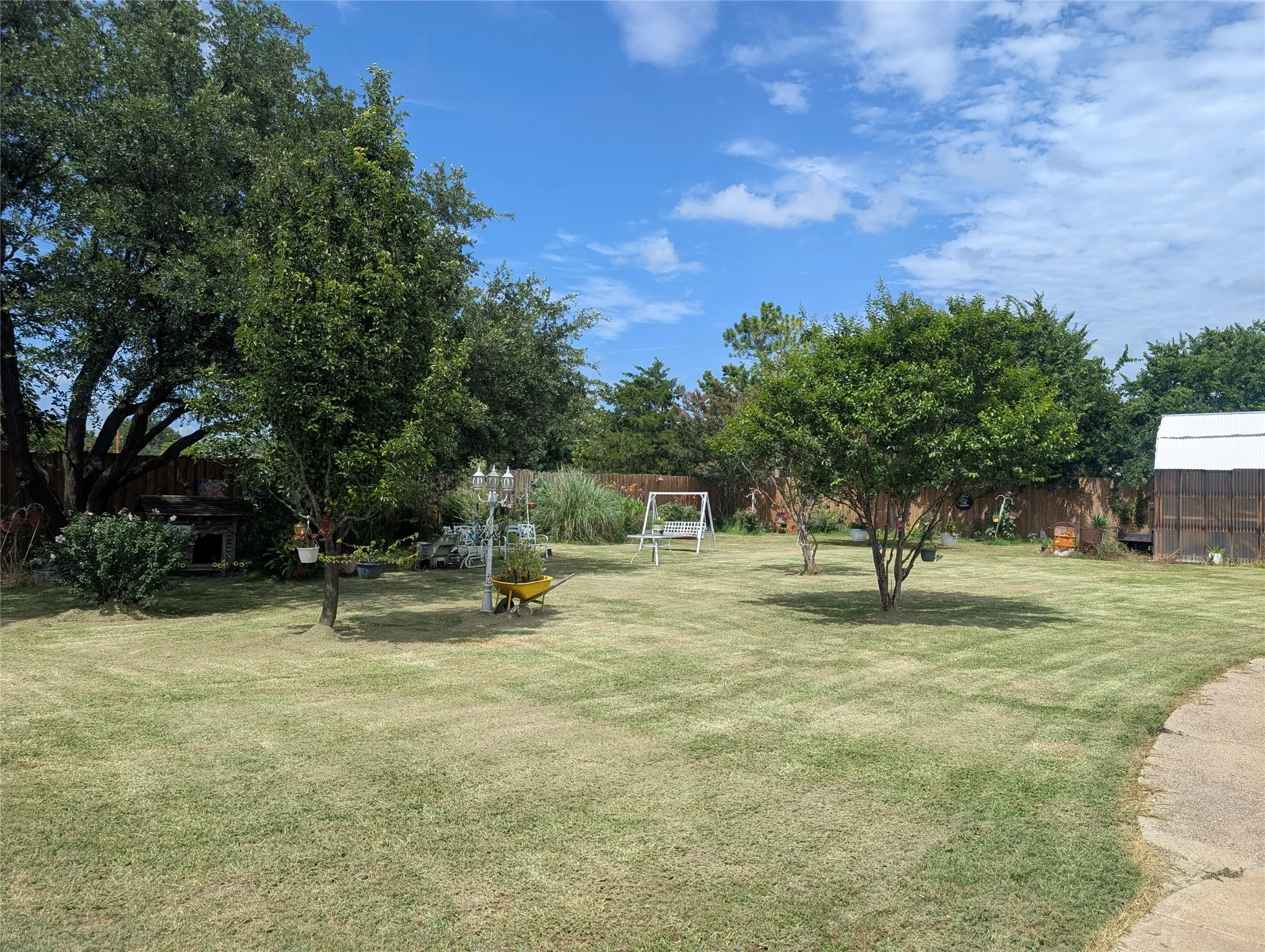 One view of the back yard.  Trees, flowers and a greenhouse