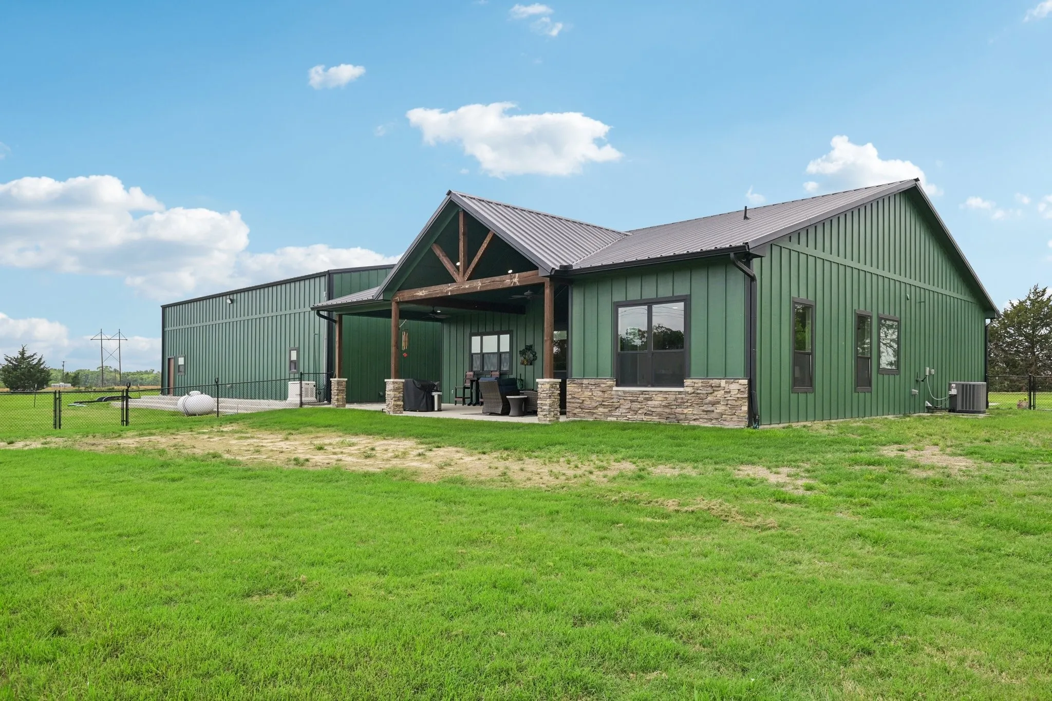 Back of the home Showcasing the Large Covered Patio, metal Roof, Stone Accents