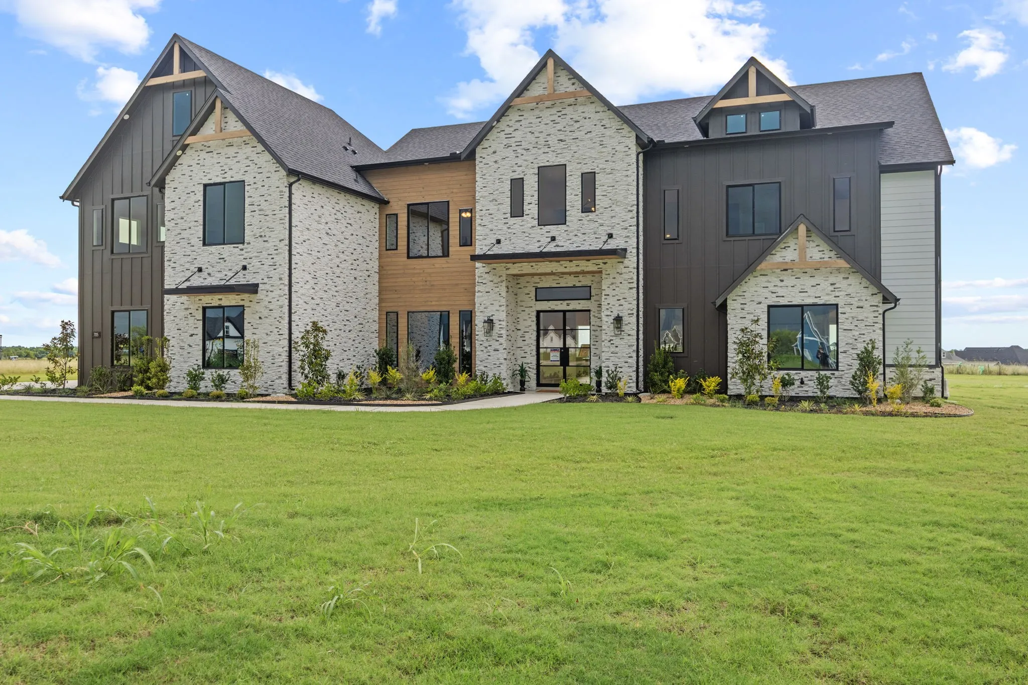Contemporary two-story exterior featuring a mix of light-colored brick, vertical dark siding, and horizontal wood paneling