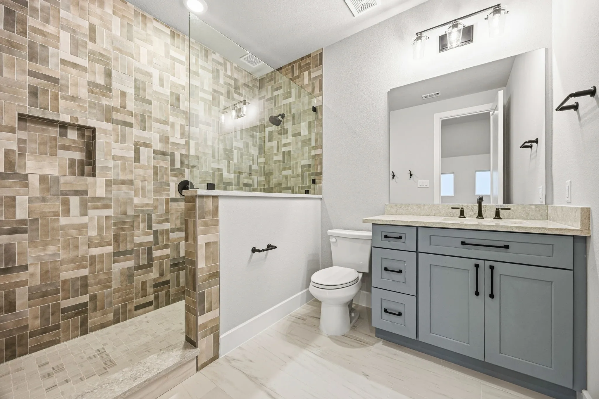 Walk-in shower with mosaic tile surround and built-in niche