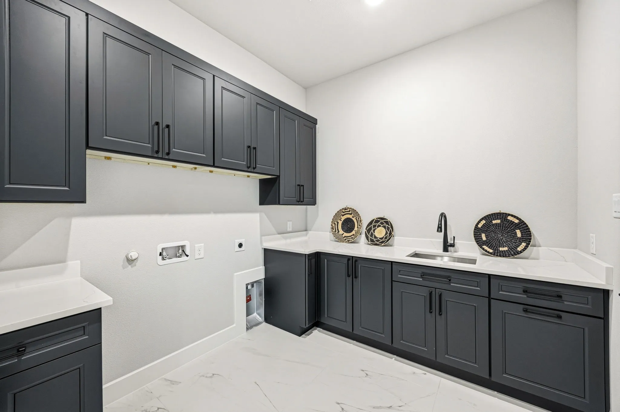 Laundry room featuring dark shaker-style cabinetry, white countertops, and white tile flooring