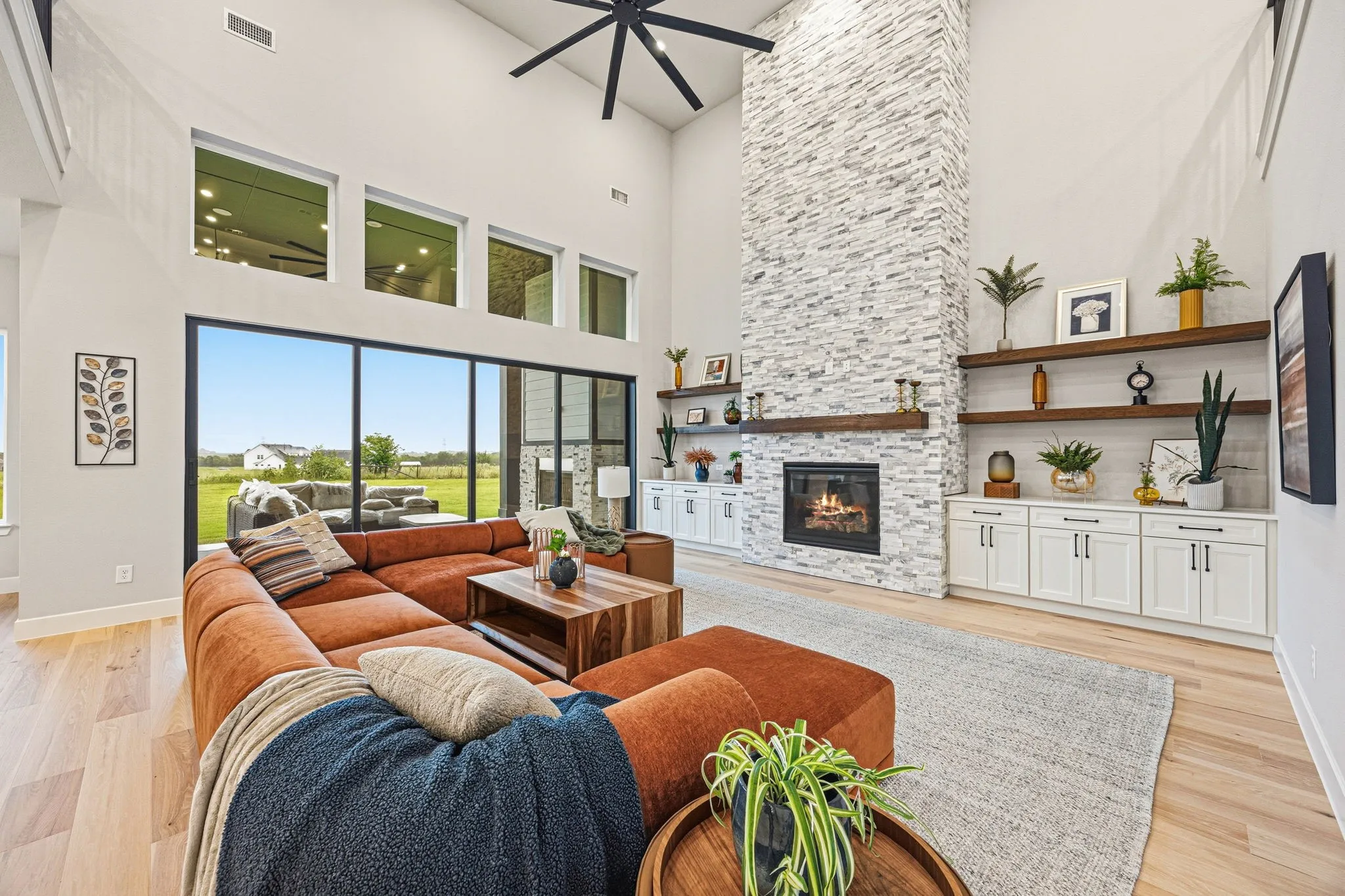 Spacious living area featuring a vaulted ceiling and a floor-to-ceiling stone-faced fireplace with a wood mantel