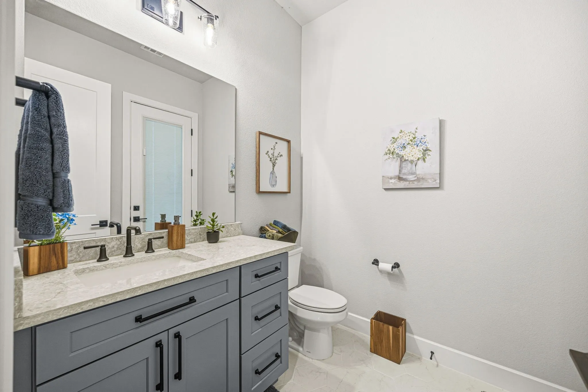 Bathroom featuring a gray vanity with black hardware, a light-colored countertop, and an undermount sink