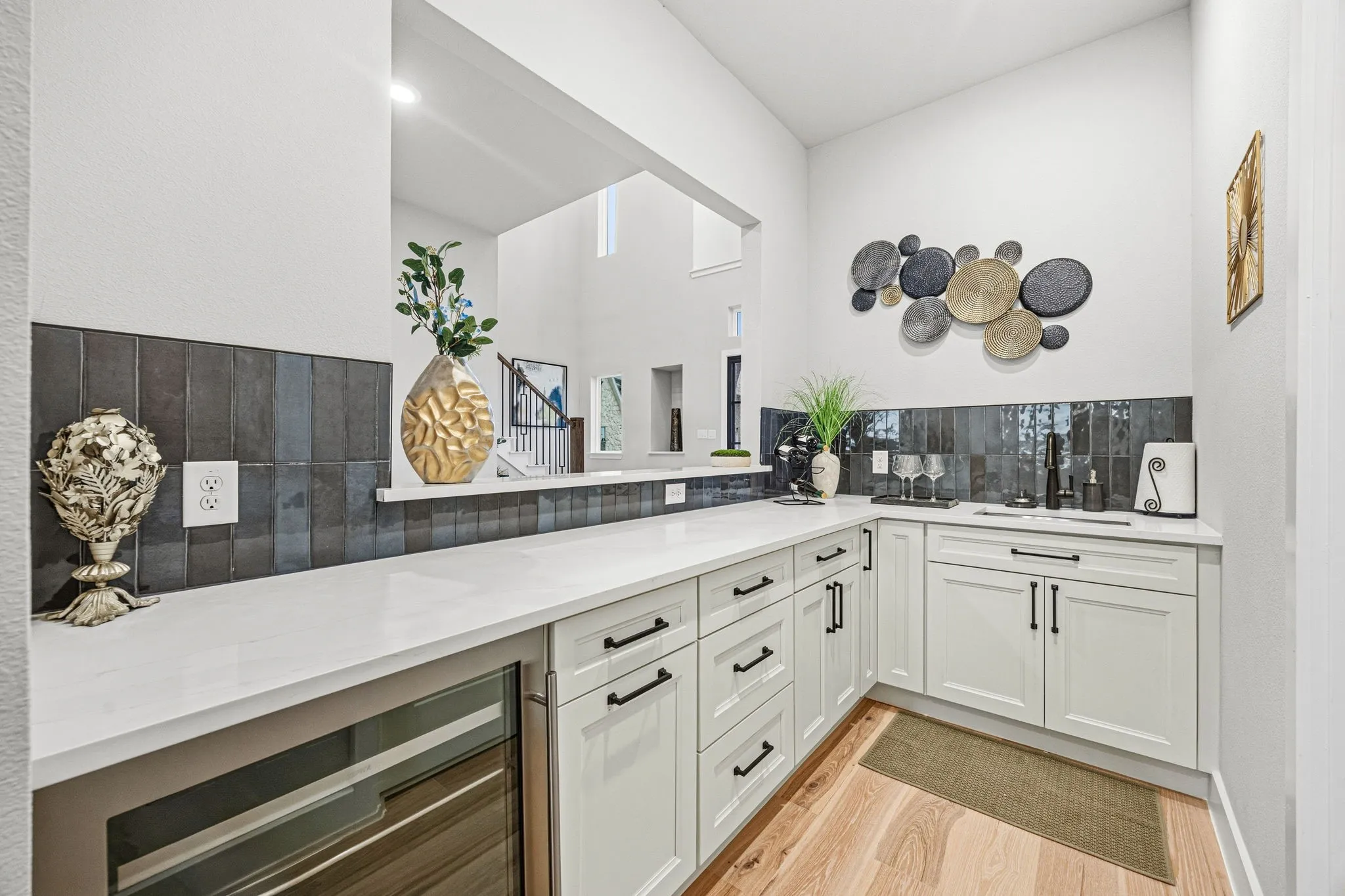 Wet bar featuring white shaker-style cabinetry, a built-in beverage refrigerator, a countertop sink, and dark subway tile backsplash