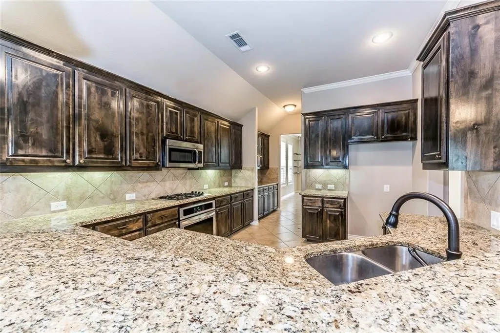 Kitchen with granite countertop, dobule bowl sink, lots of cabinets and bulter's pantry in the background.