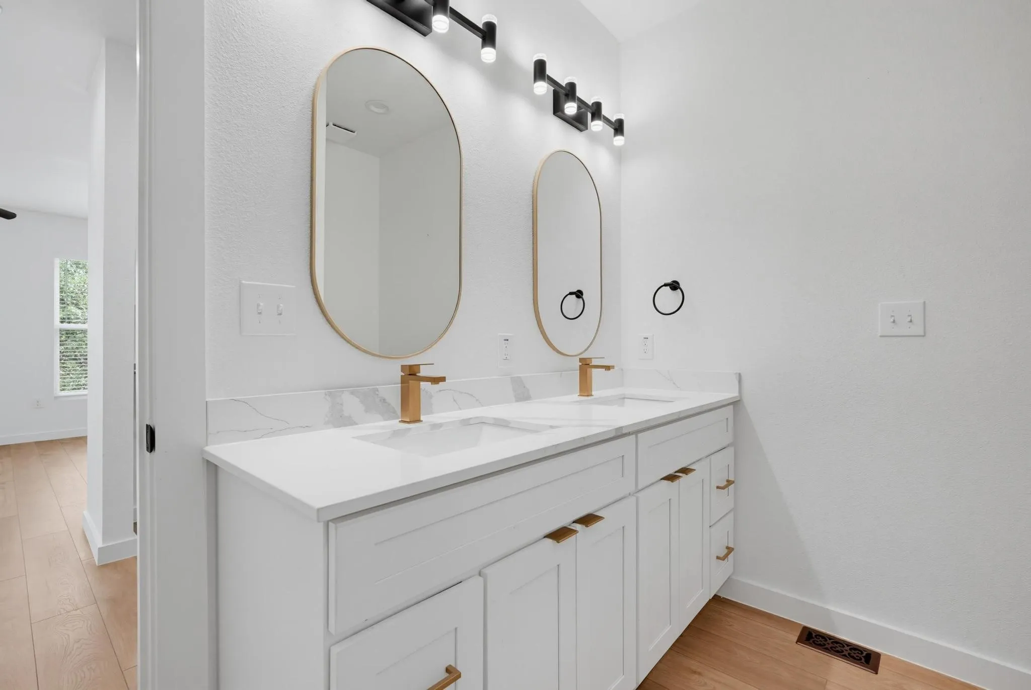 Dual vanity with white cabinetry, gold-finish hardware, and a white countertop with integrated sinks