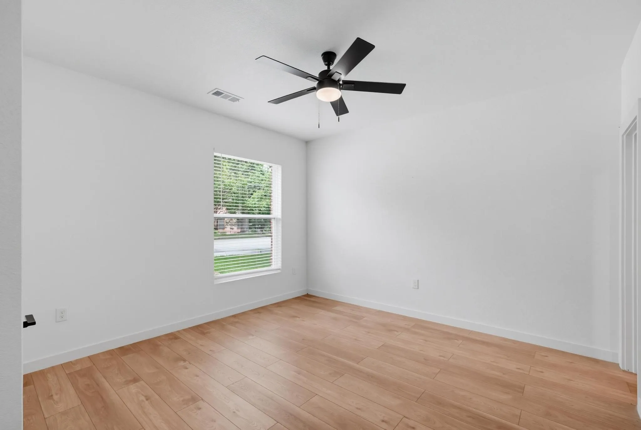 Wood-finish flooring, white baseboards, and a window with horizontal blinds