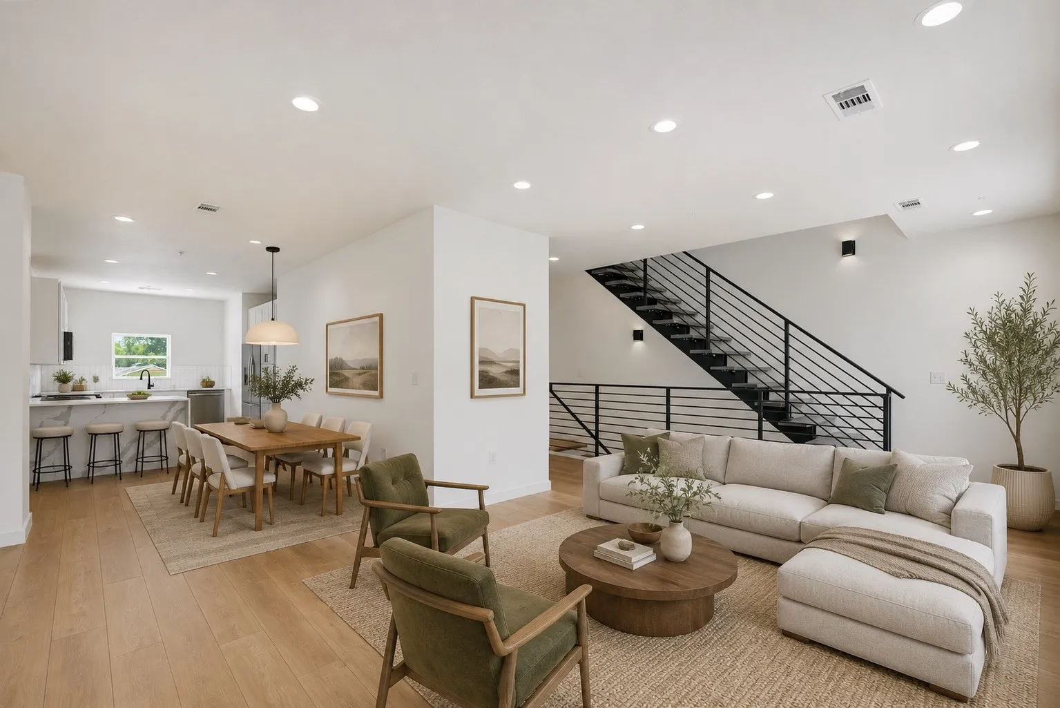 Open-concept living area featuring light wood-finish flooring, recessed lighting, and a contemporary staircase with black metal railings