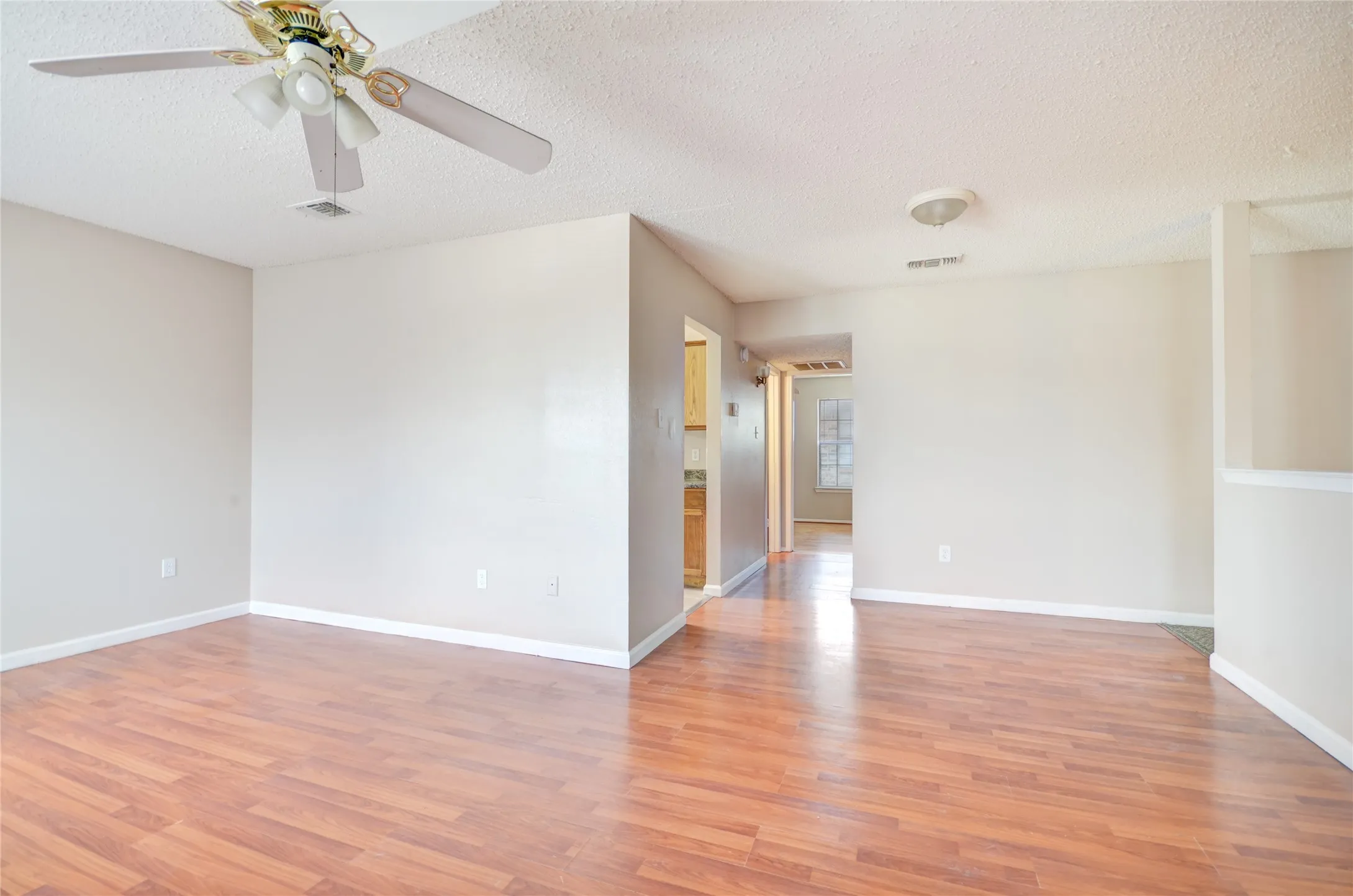Open living area featuring luxury plank flooring, light neutral walls, and a ceiling fan with integrated lighting