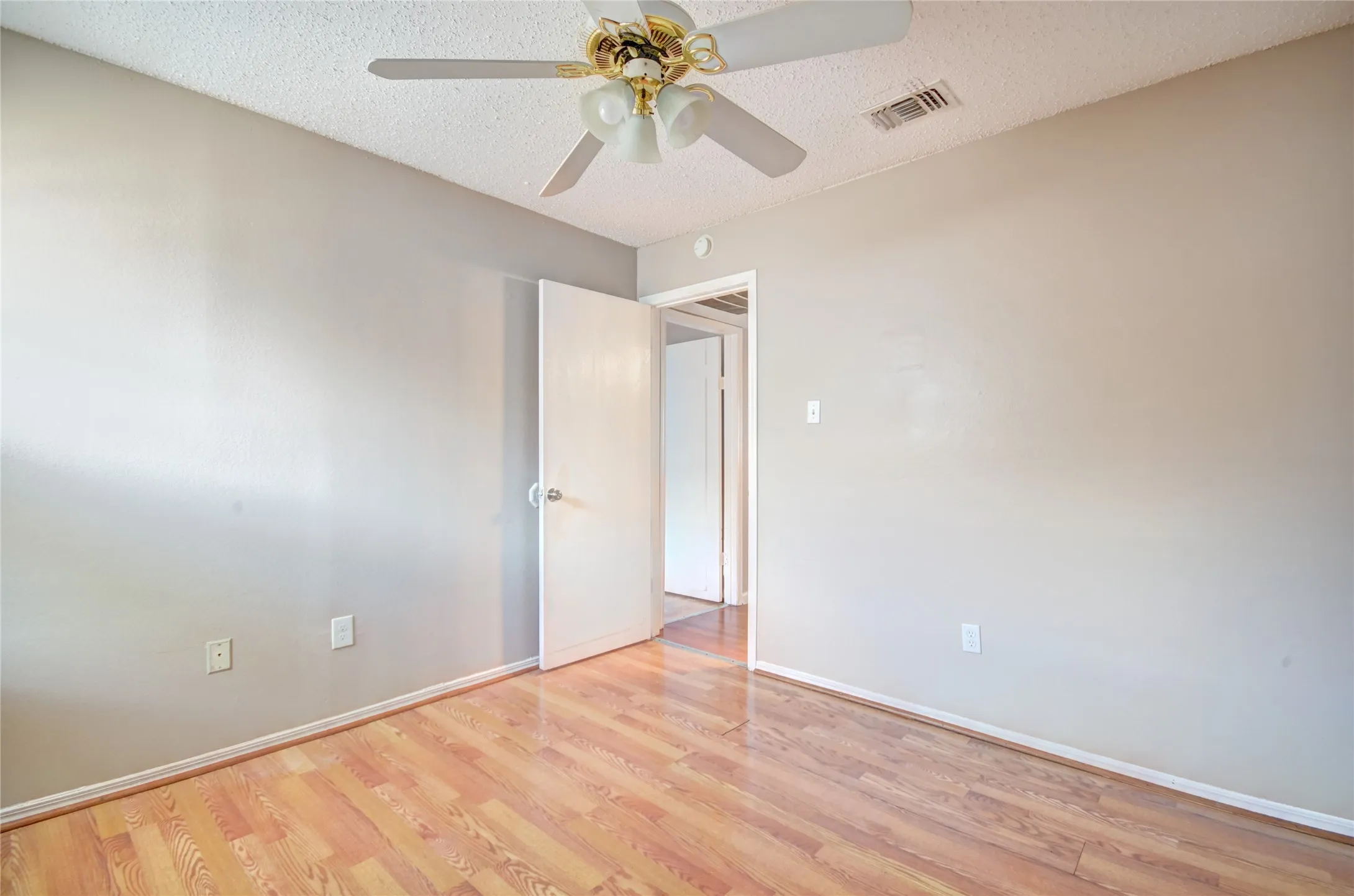 Second bedroom featuring luxury plank flooring, closet, light neutral wall tones, and a ceiling fan with integrated lighting