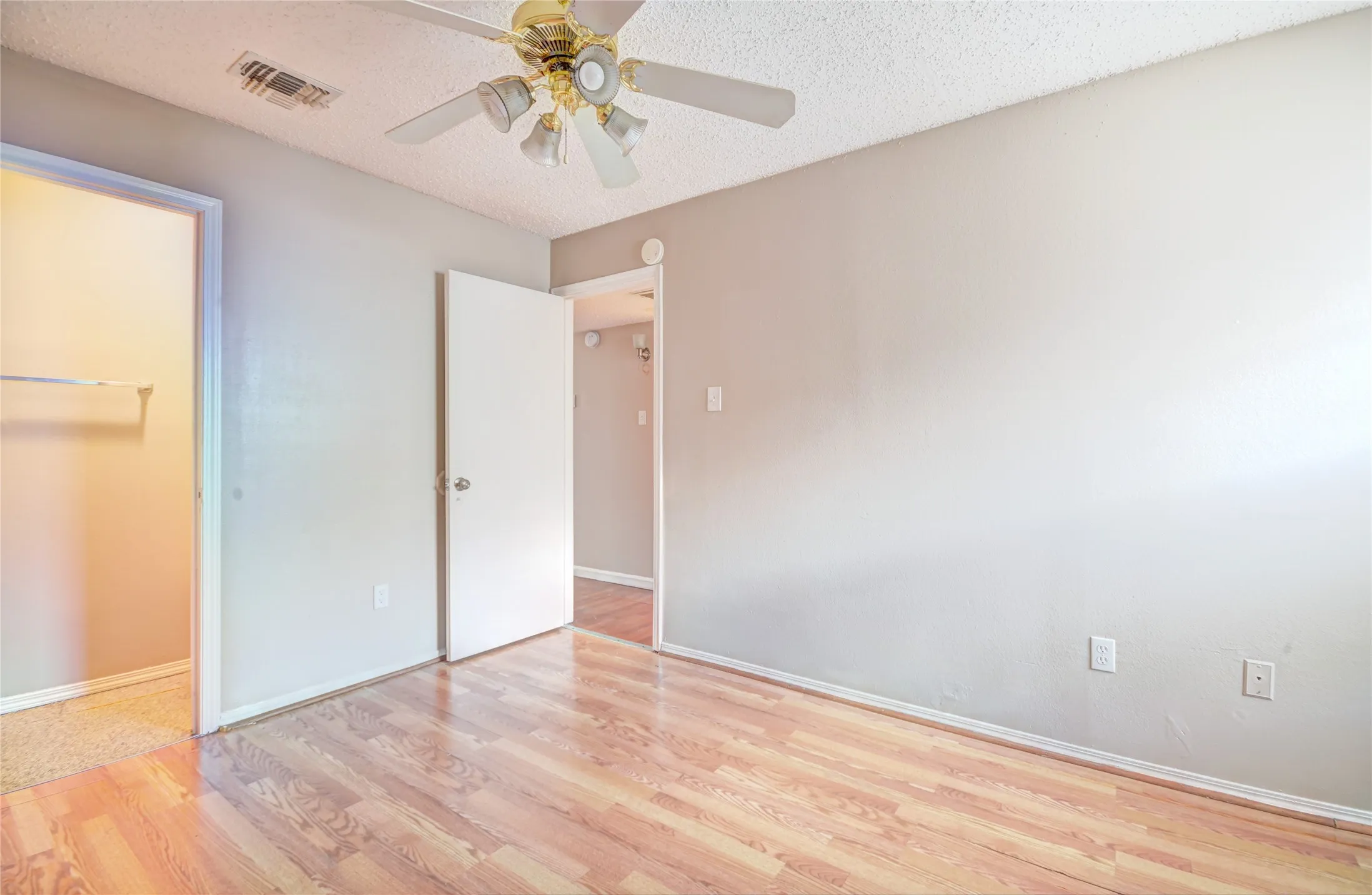 Primary bedroom featuring luxury plank flooring, half bath, light neutral wall tones, and a ceiling fan with integrated lighting