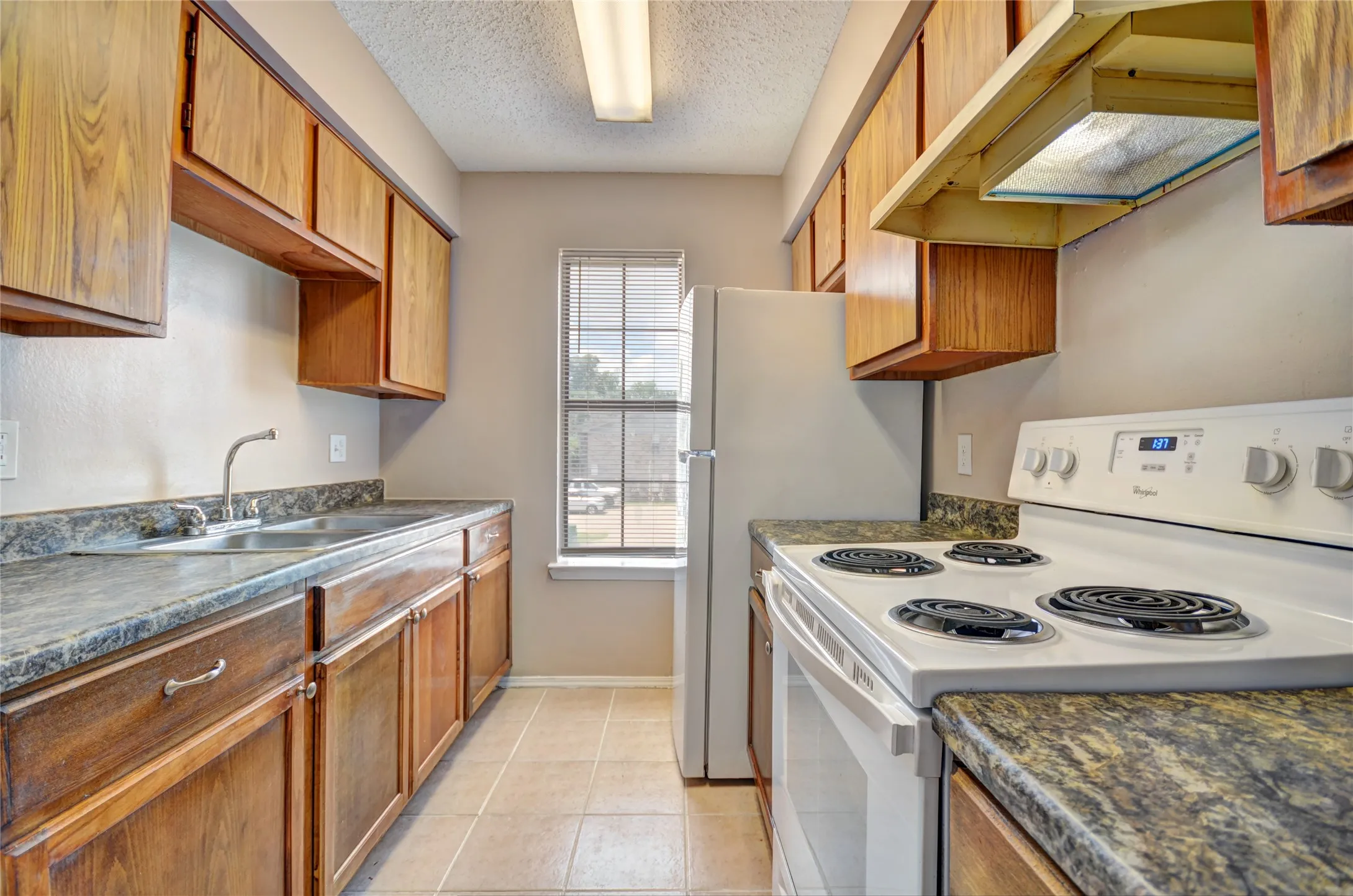 Kitchen featuring wood-finish cabinetry, upgraded countertops, and tile flooring