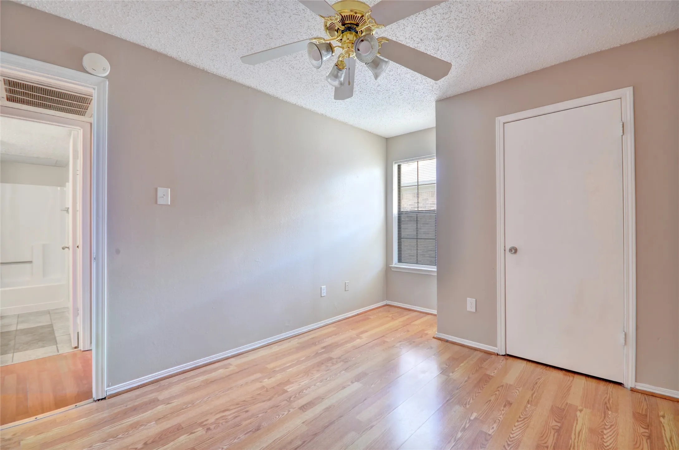 Second bedroom featuring luxury plank flooring, closet, light neutral wall tones, and a ceiling fan with integrated lighting