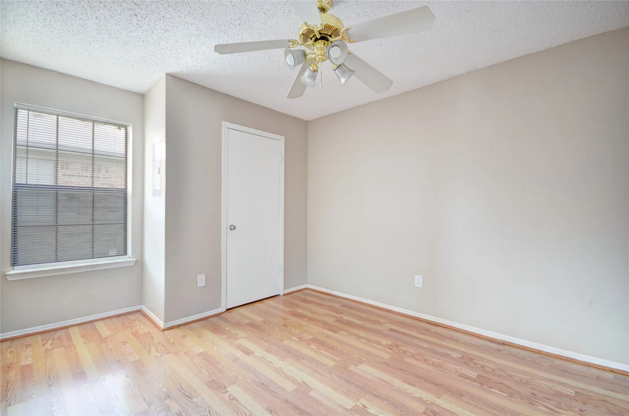 Primary bedroom featuring luxury plank flooring, closet, light neutral wall tones, and a ceiling fan with integrated lighting