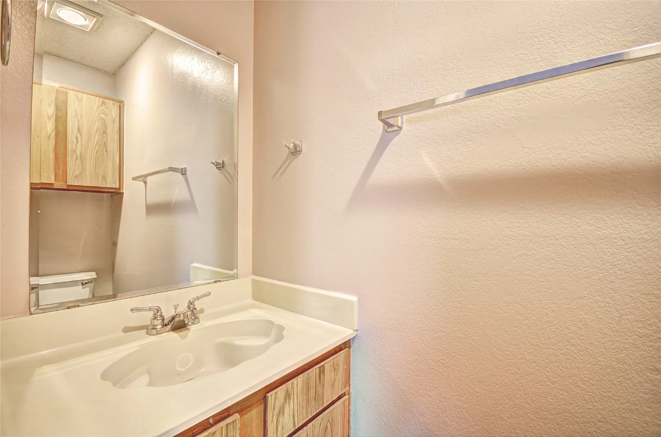 Half bathroom includes vanity with an integrated white sink and chrome faucet, set against a full-width mirror