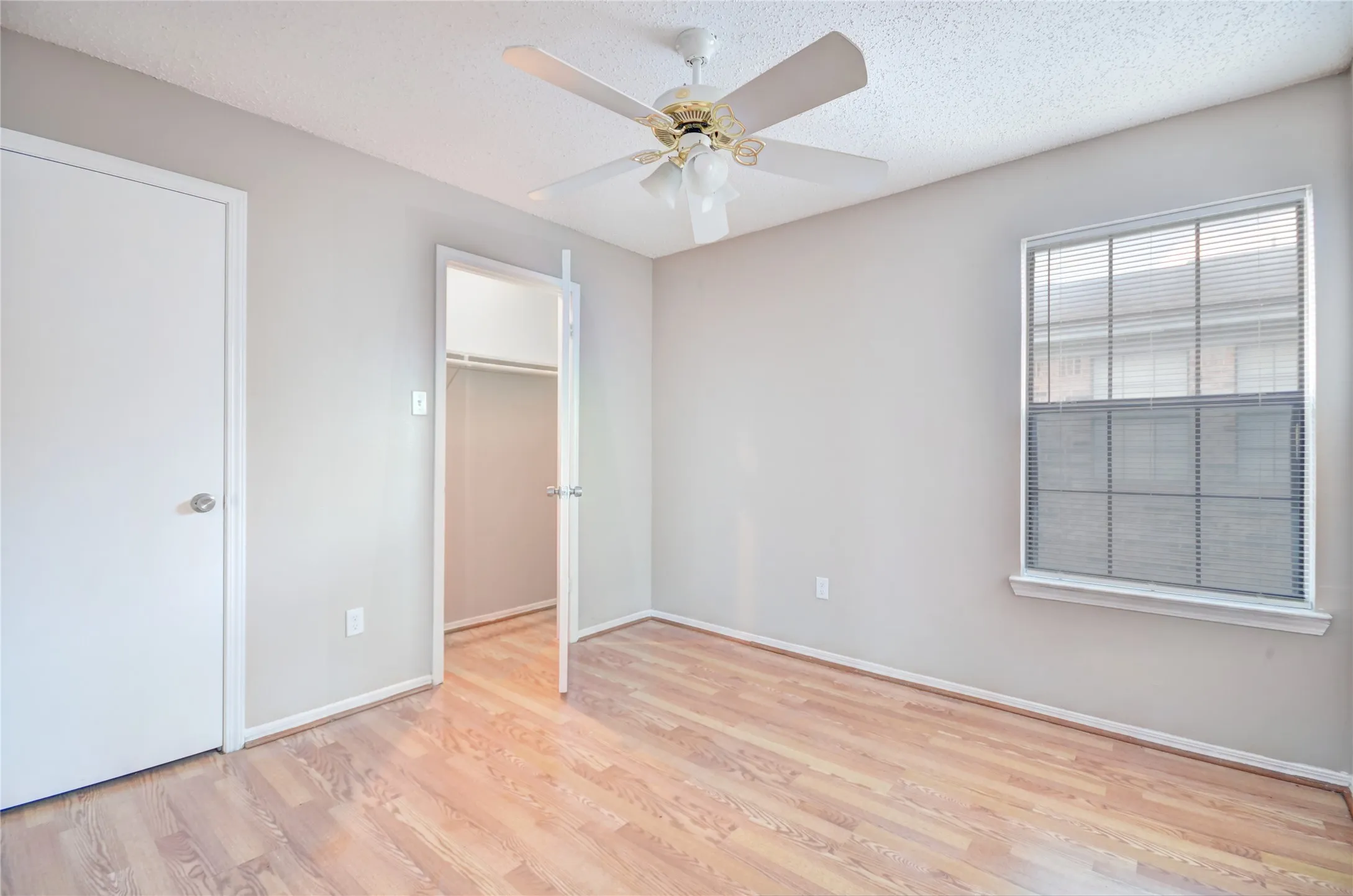 Second bedroom featuring luxury plank flooring, closet, light neutral wall tones, and a ceiling fan with integrated lighting