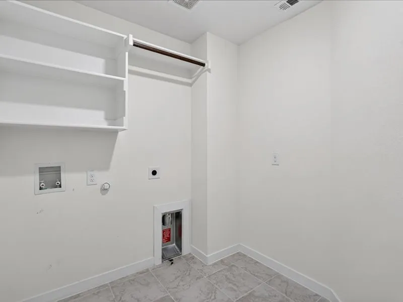 Utility area with light gray tile flooring, built-in shelving, and a hanging rod