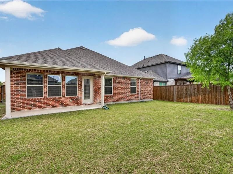 Expansive rear yard featuring a large grass area, wood privacy fencing, and a concrete patio