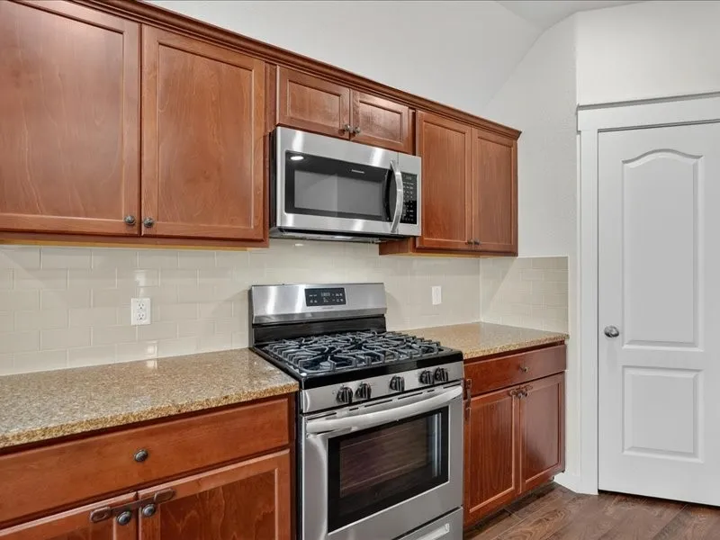 Kitchen featuring rich wood cabinetry, stainless steel appliances, a gas range, and light-toned subway tile backsplash