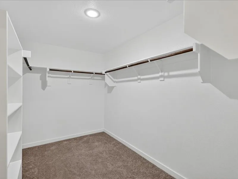 Walk-in closet featuring built-in shelving, hanging rods, recessed lighting, and textured walls