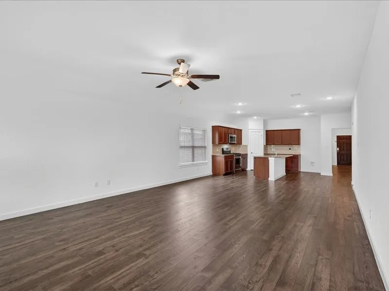 Open-concept living space featuring wood-finish flooring, a ceiling fan with integrated lighting, and recessed lighting