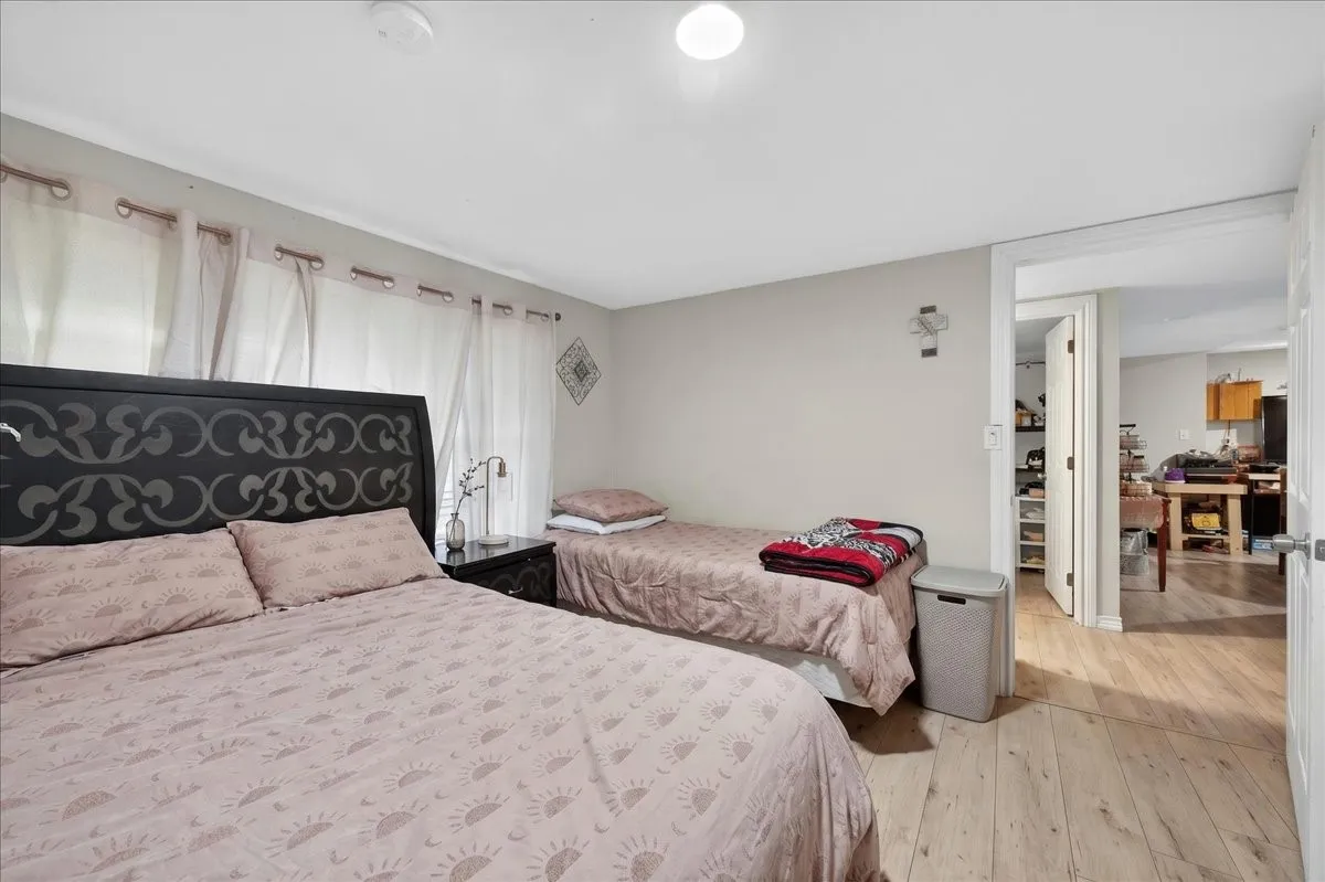 Laminate wood-finish flooring extends throughout this room, featuring light gray walls, a flush-mount ceiling light, and window treatments