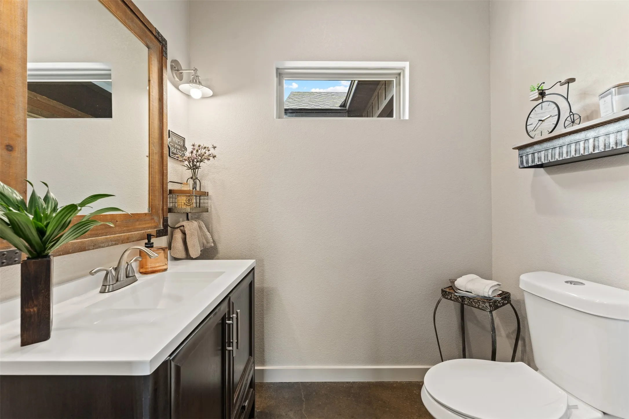 Powder room featuring a dark wood-finish vanity with a white countertop, chrome faucet, and a rectangular wood-framed mirror
