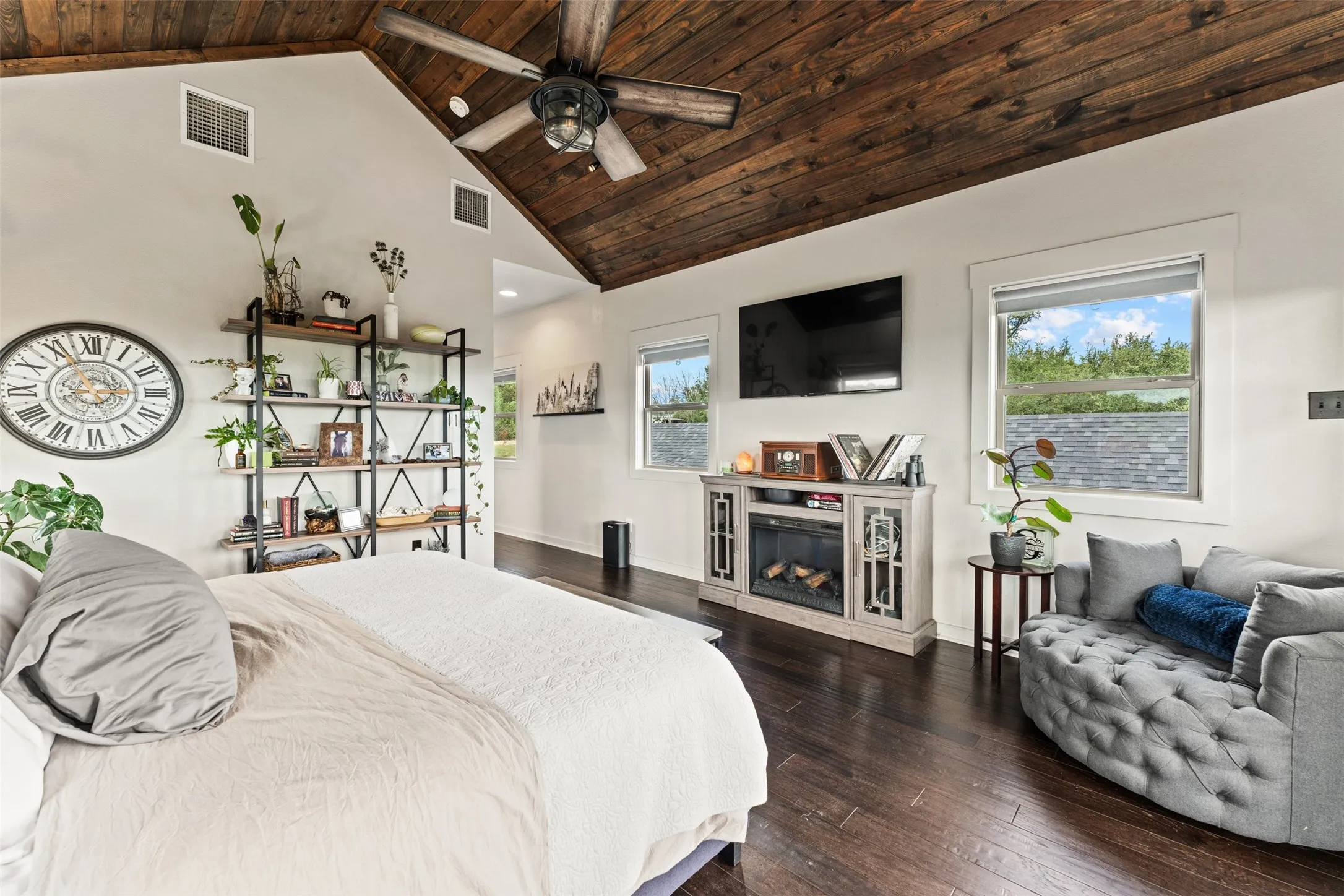 Vaulted wood-plank ceiling with a ceiling fan, dark wood-finish flooring, and white walls