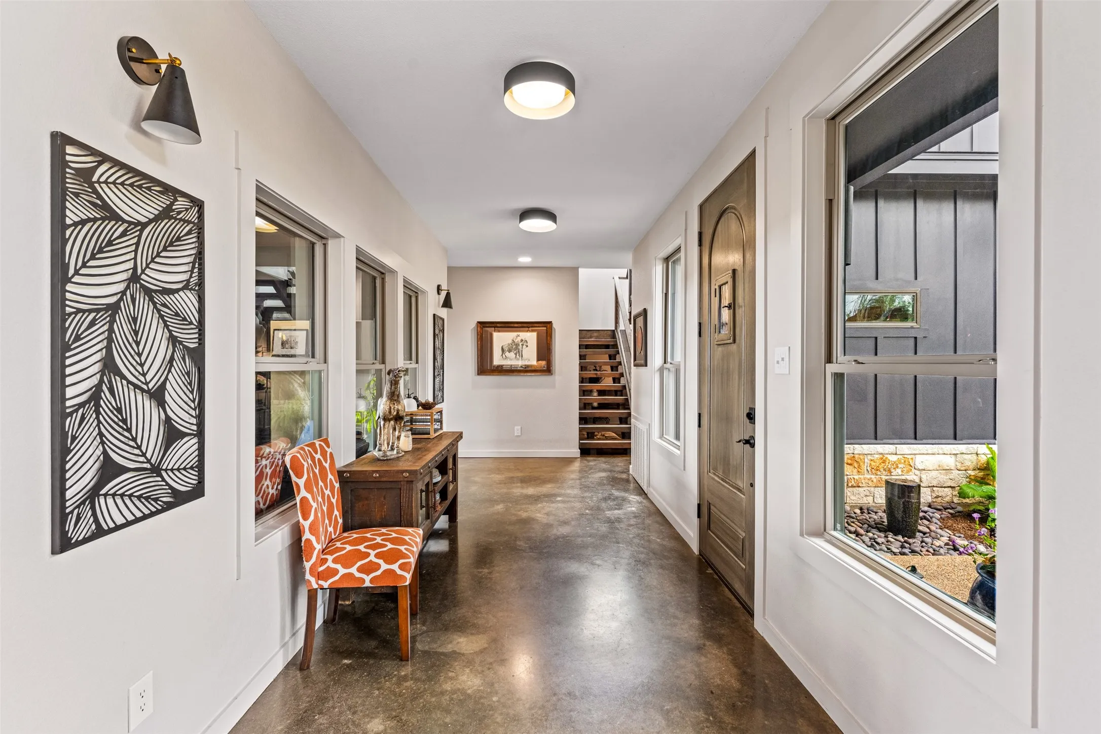 Interior hallway featuring polished concrete flooring, a series of windows, and contemporary wall sconces
