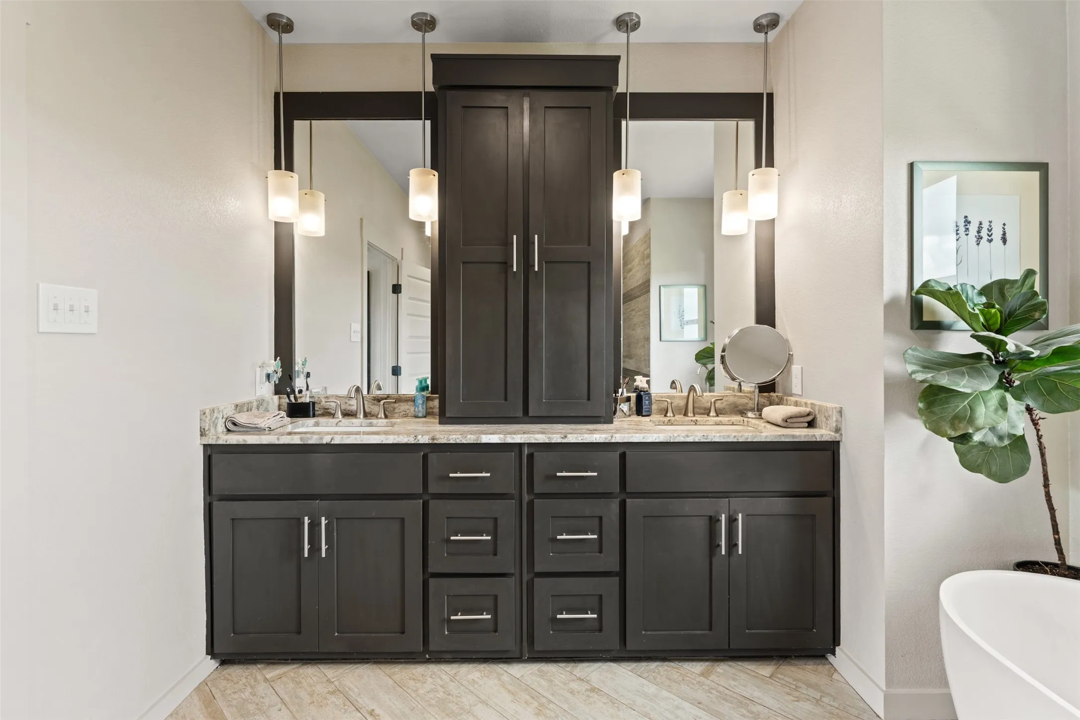 Dual vanity featuring dark wood cabinetry and a central storage tower