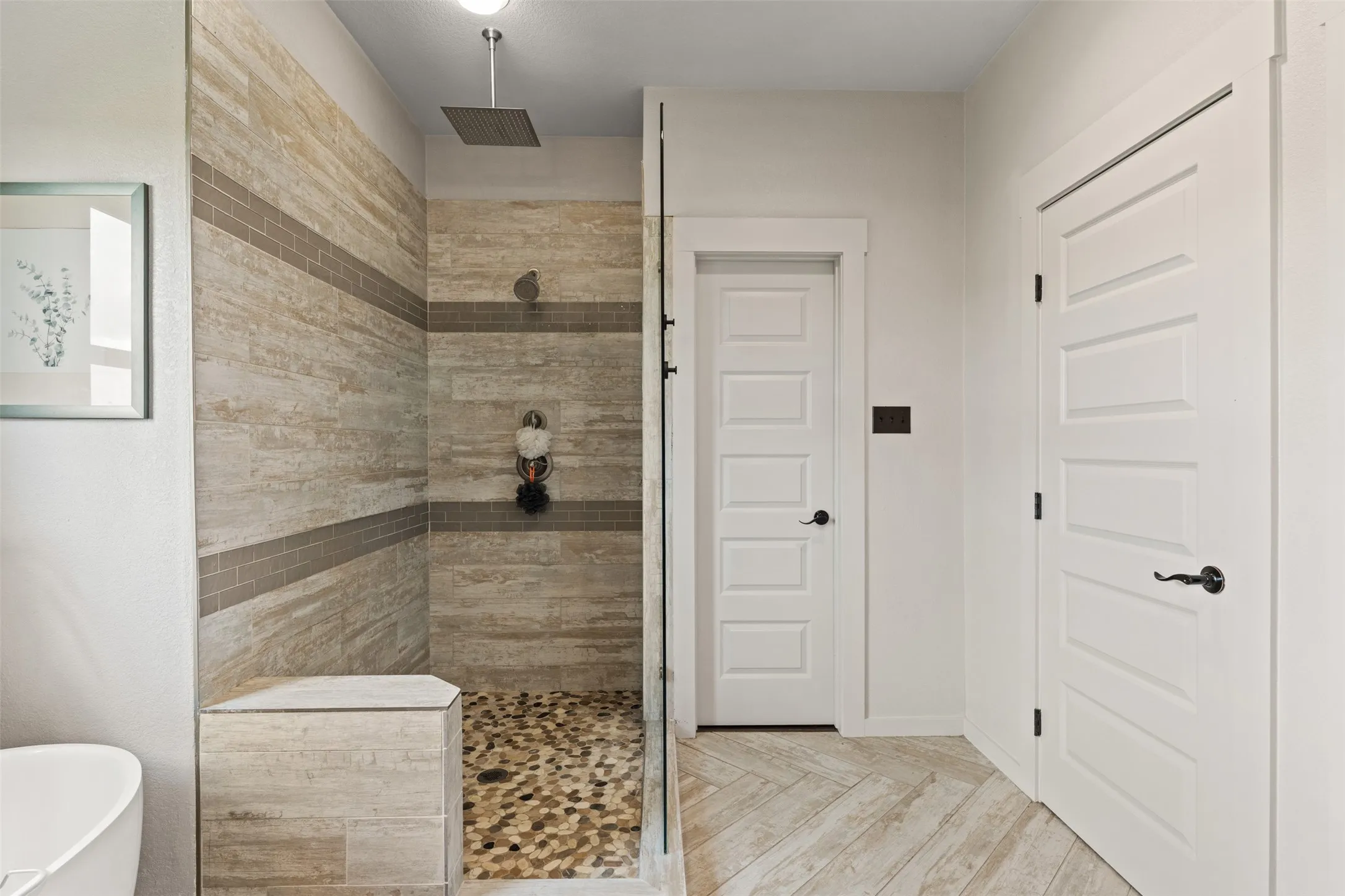 Walk-in shower with natural-toned stone tile walls and horizontal accent bands