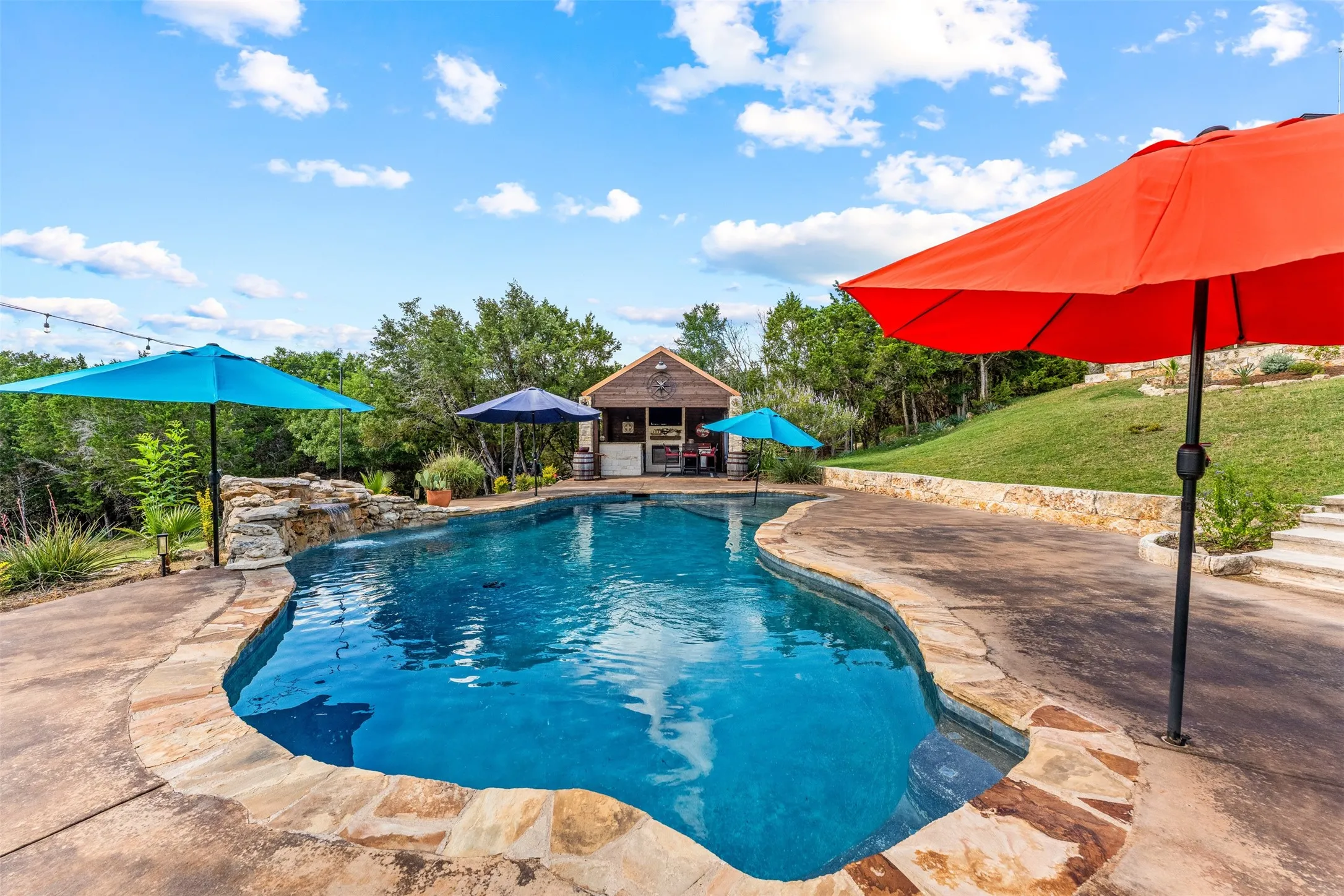 Freeform swimming pool featuring a natural rock waterfall