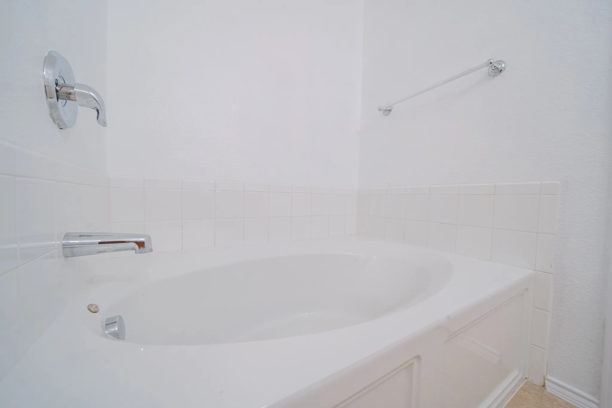 Built-in bathtub with a white tiled surround and chrome fixtures