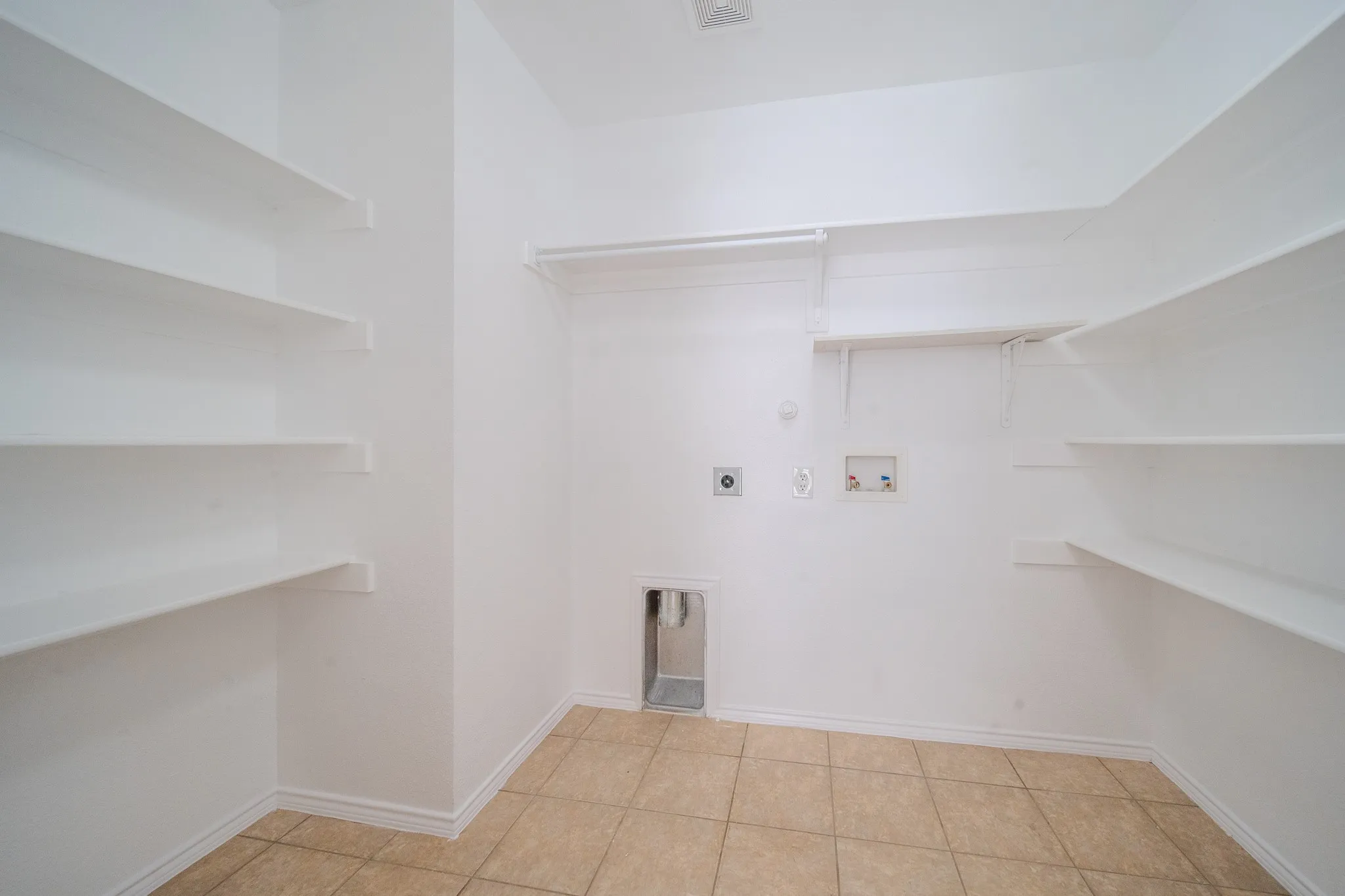 Dedicated laundry area featuring tile flooring, built-in shelving, a clothes rod, and appliance hookups
